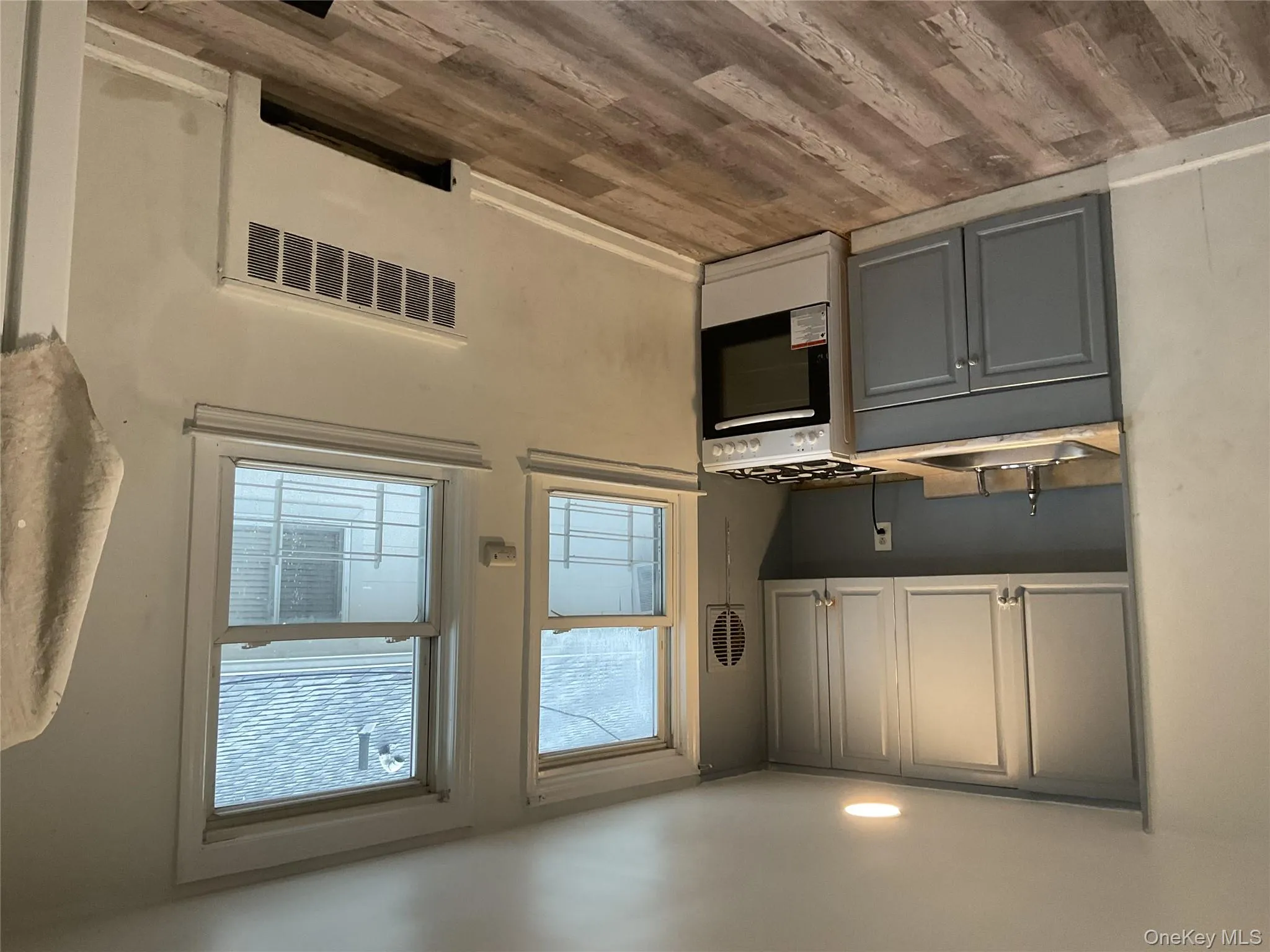 Kitchen with gray cabinets, radiator heating unit, light countertops, stove, and light wood finished floors Kitchen with gray cabinets, radiator heating unit, light countertops, stove, and light wood finished floors