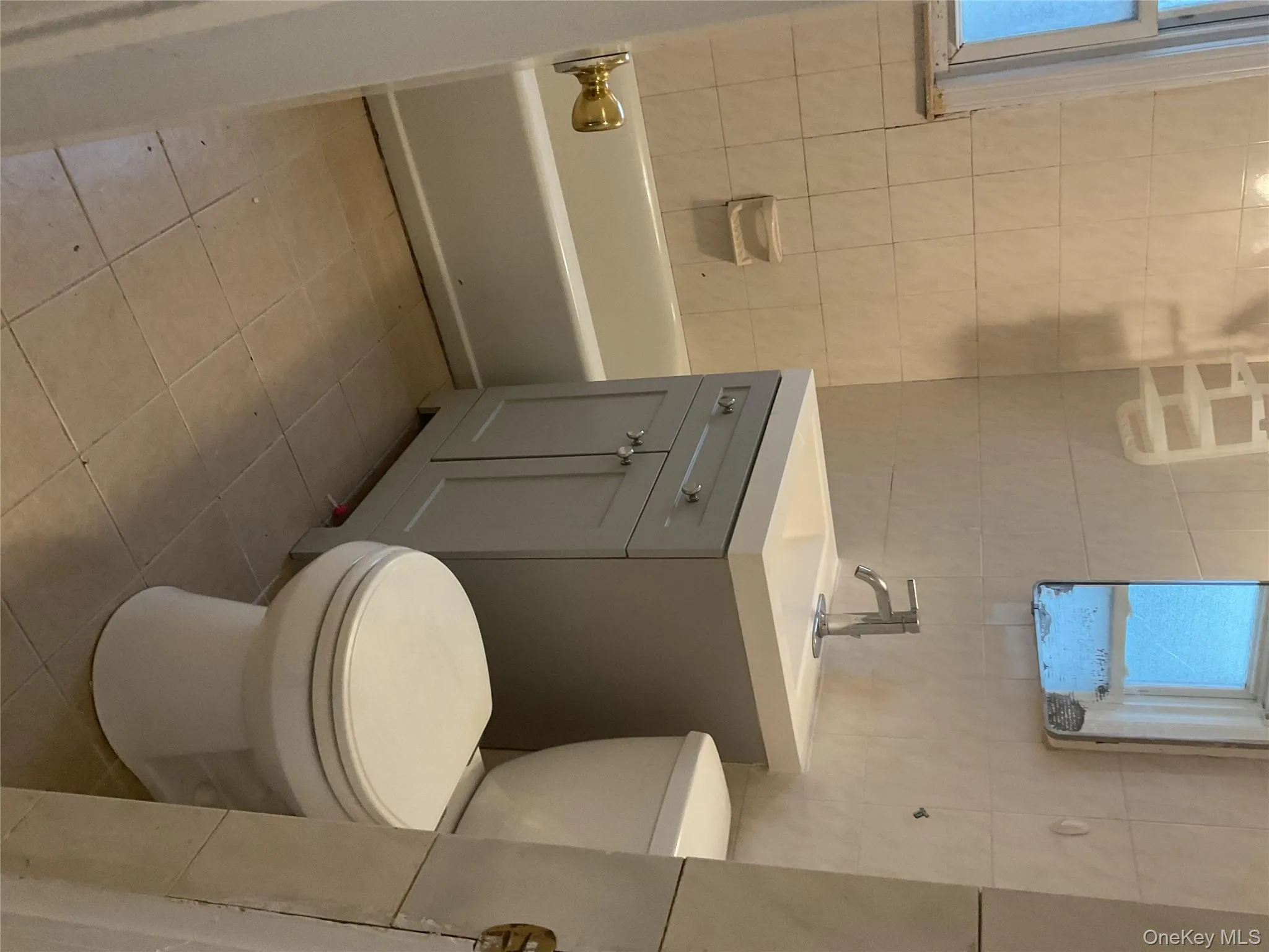 Bathroom with vanity, tile walls, light tile patterned flooring, and washtub / shower combination Bathroom with vanity, tile walls, light tile patterned flooring, and washtub / shower combination