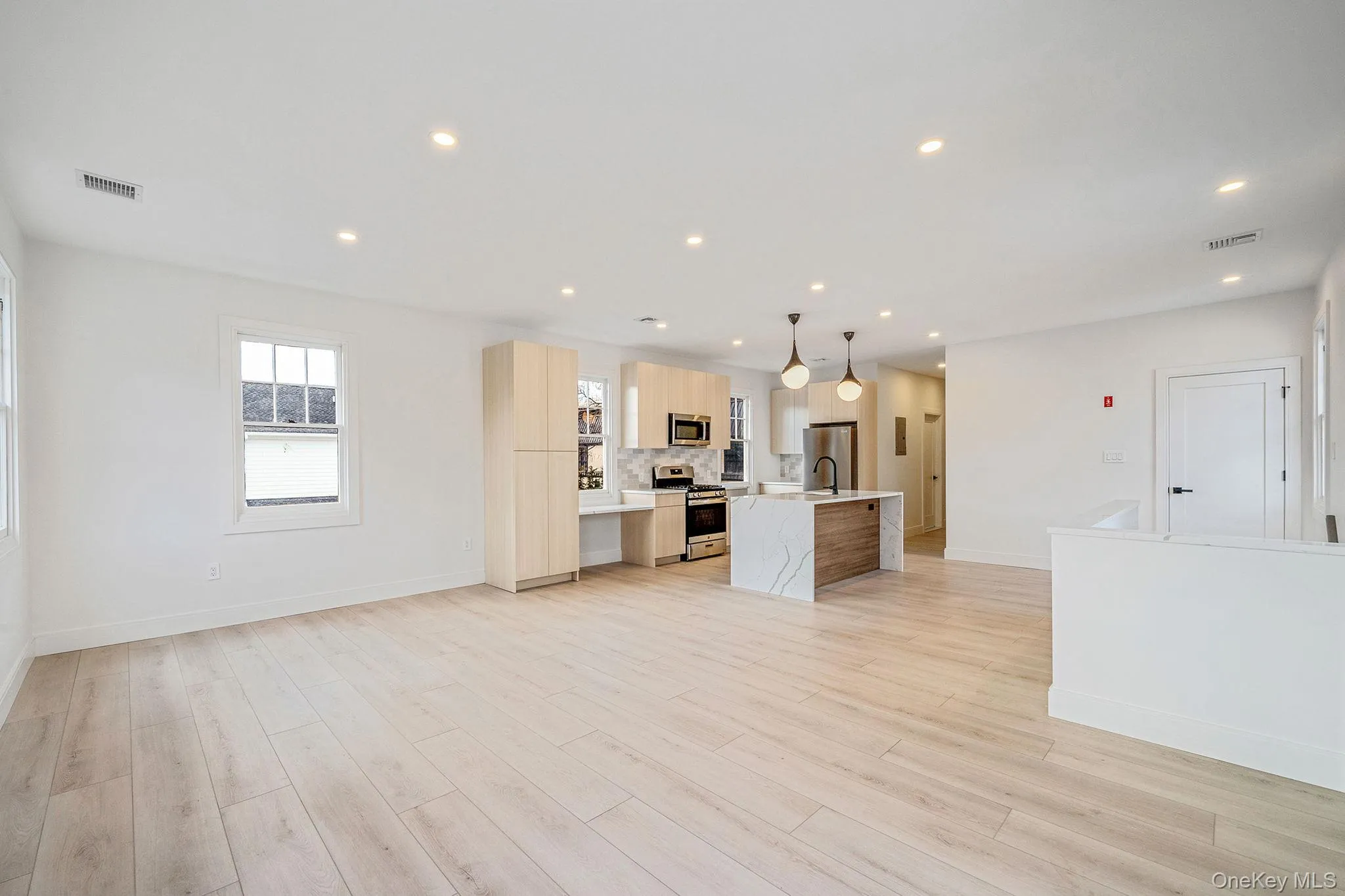 Kitchen with hanging light fixtures, appliances with stainless steel finishes, recessed lighting, modern cabinets, and light wood-style floors Kitchen with hanging light fixtures, appliances with stainless steel finishes, recessed lighting, modern cabinets, and light wood-style floors