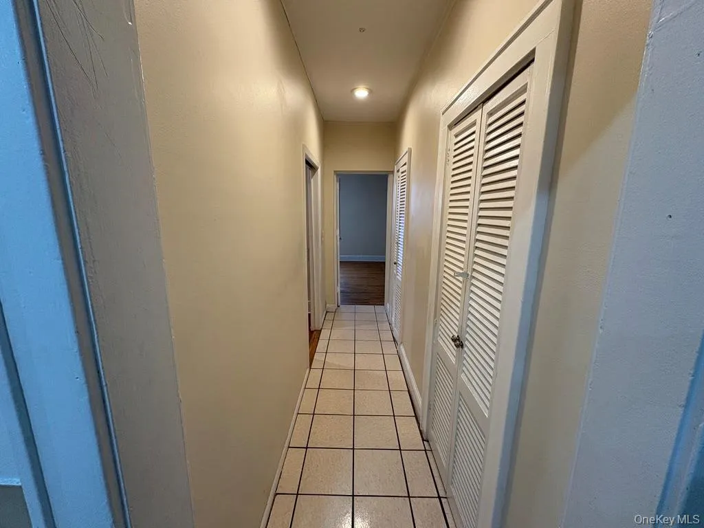 Hallway with light tile patterned floors and baseboards Hallway with light tile patterned floors and baseboards