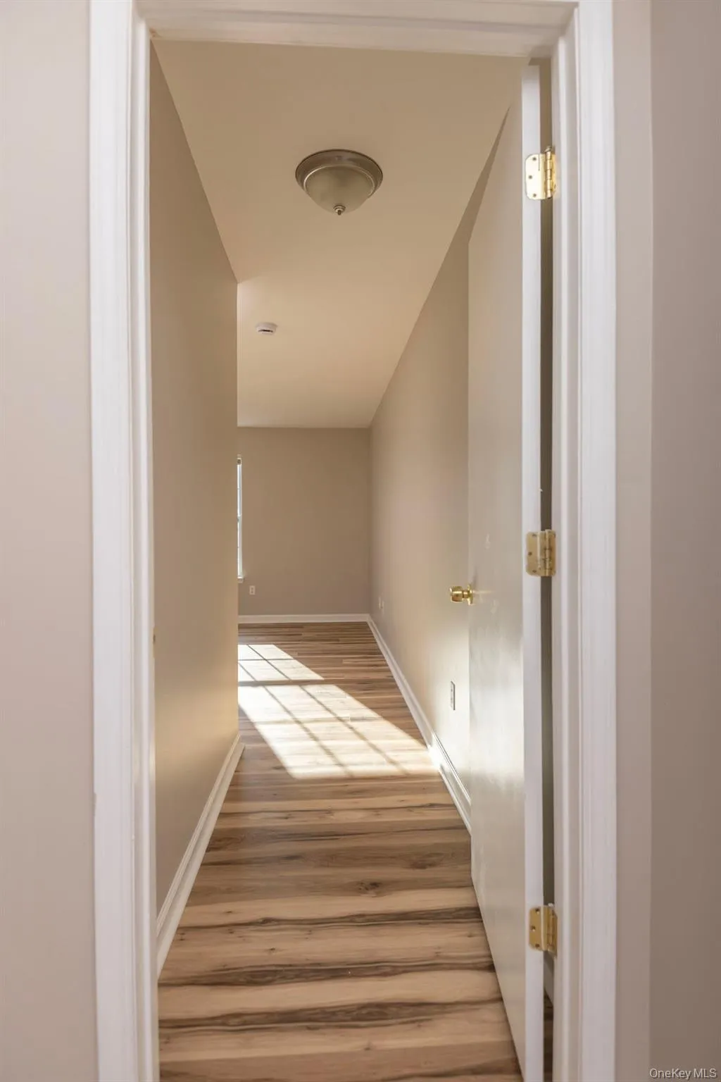 Hallway featuring light wood-type flooring and baseboards Hallway featuring light wood-type flooring and baseboards