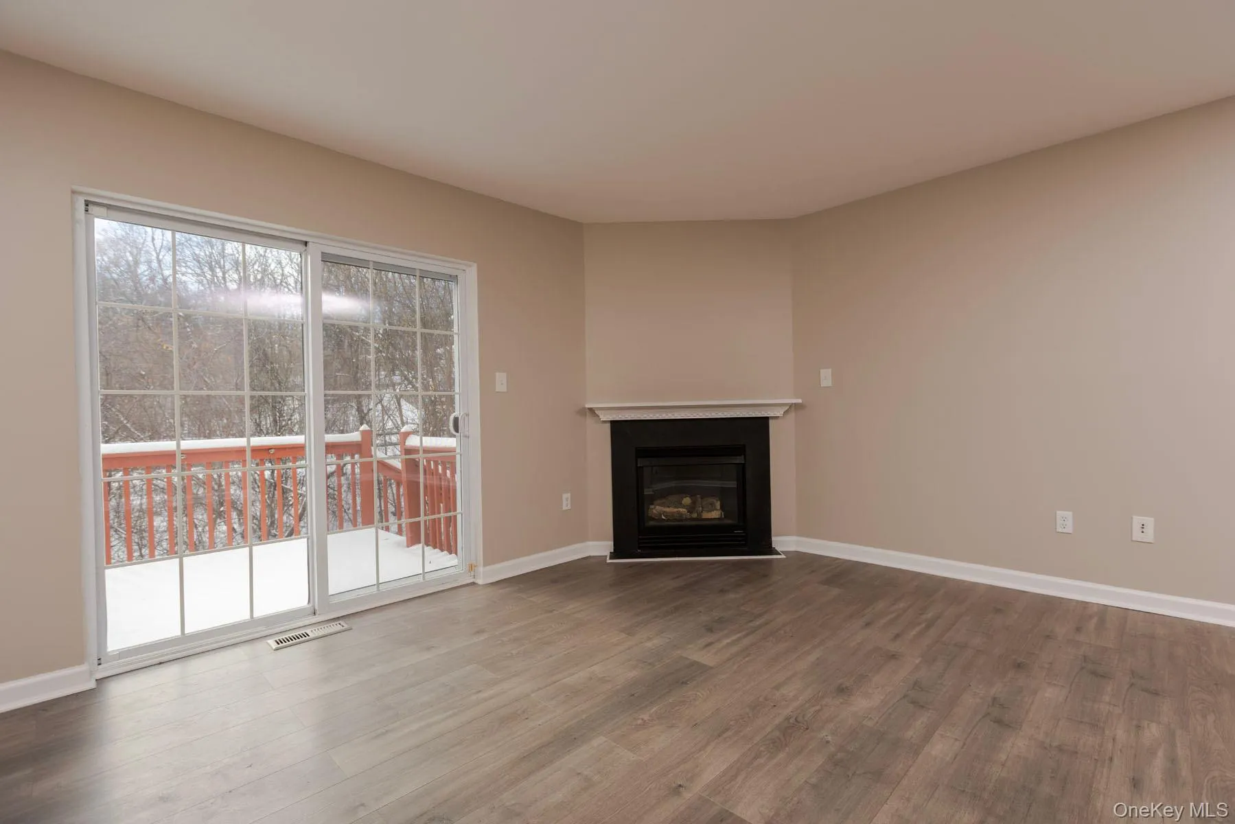 Unfurnished living room featuring a glass covered fireplace and wood finished floors Unfurnished living room featuring a glass covered fireplace and wood finished floors