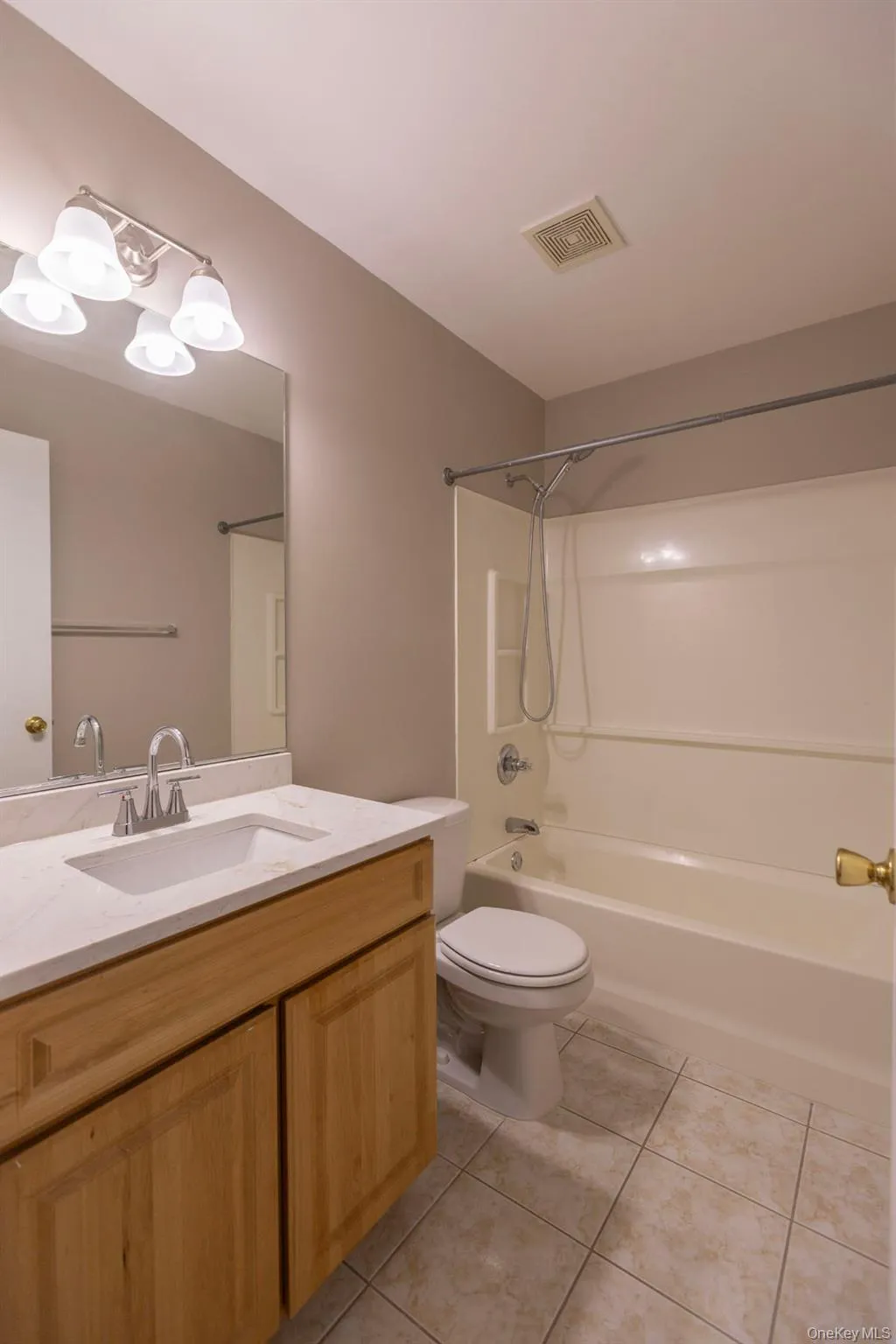 Bathroom with washtub / shower combination, vanity, and light tile patterned floors Bathroom with washtub / shower combination, vanity, and light tile patterned floors