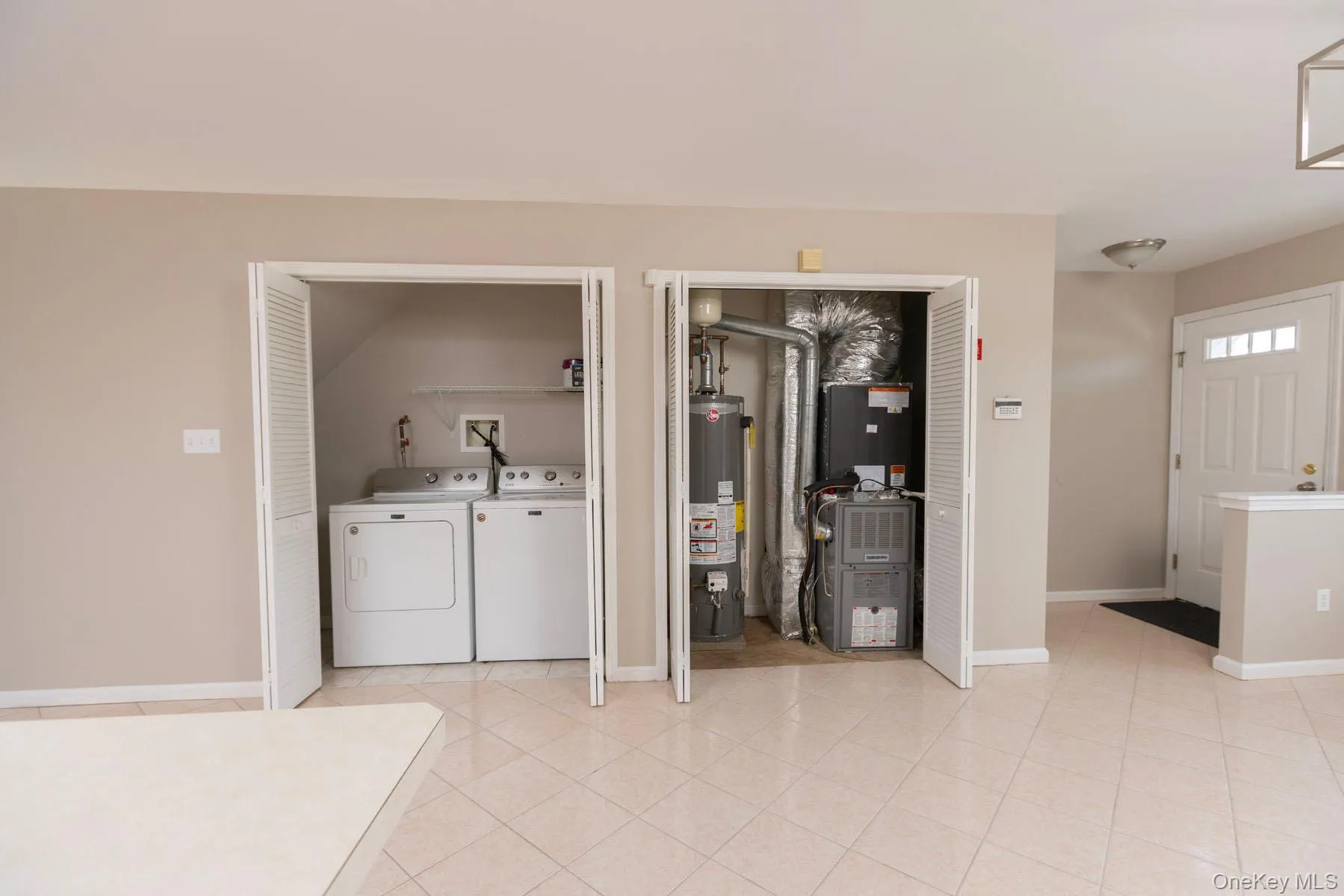 Laundry area with gas water heater, heating unit, washing machine and clothes dryer, and light tile patterned floors Laundry area with gas water heater, heating unit, washing machine and clothes dryer, and light tile patterned floors