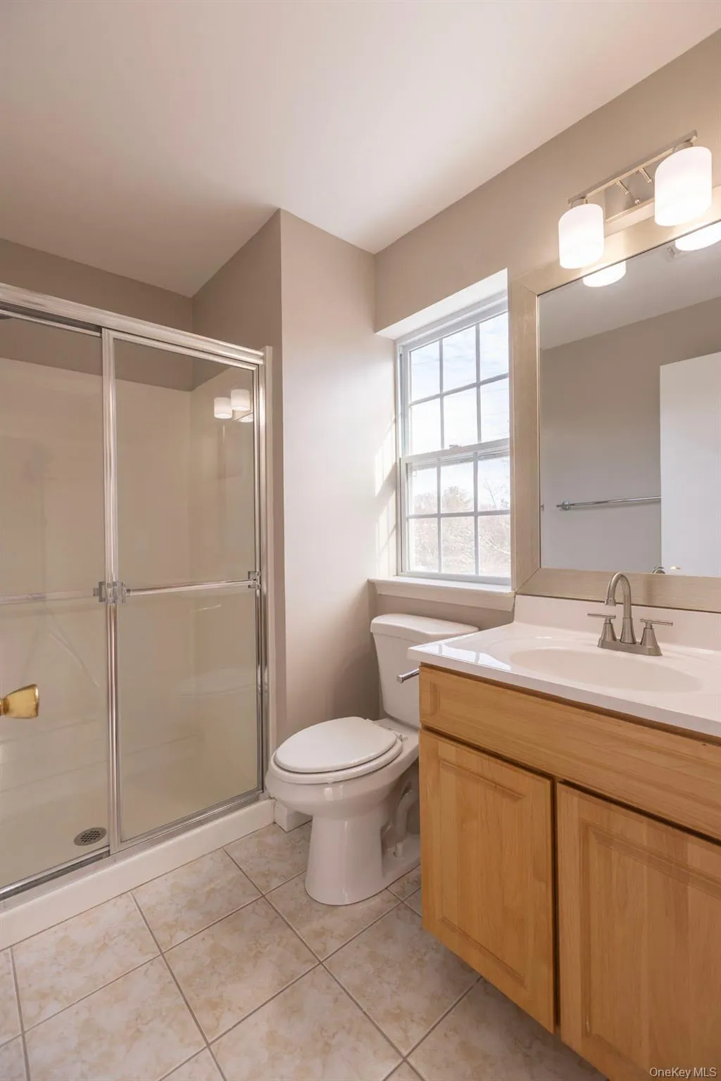 Full bath featuring vanity, a shower stall, and light tile patterned floors Full bath featuring vanity, a shower stall, and light tile patterned floors