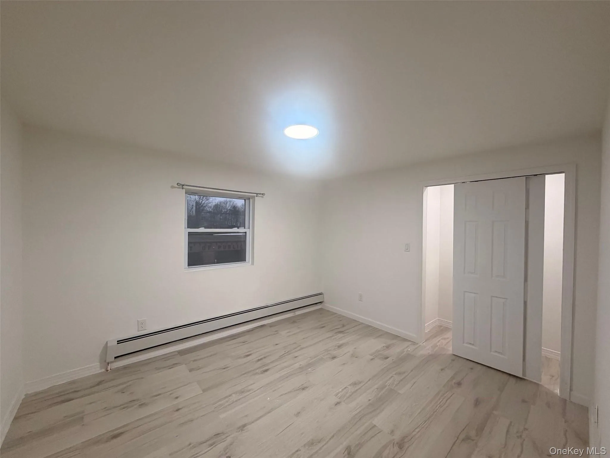 Bedroom with a baseboard radiator and light wood finished floors Bedroom with a baseboard radiator and light wood finished floors