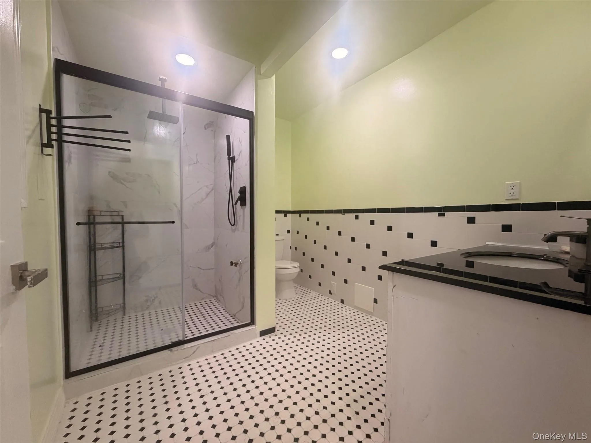 First floor Bathroom featuring vanity, a marble finish shower, recessed lighting, tile walls, and a wainscoted wall First floor Bathroom featuring vanity, a marble finish shower, recessed lighting, tile walls, and a wainscoted wall