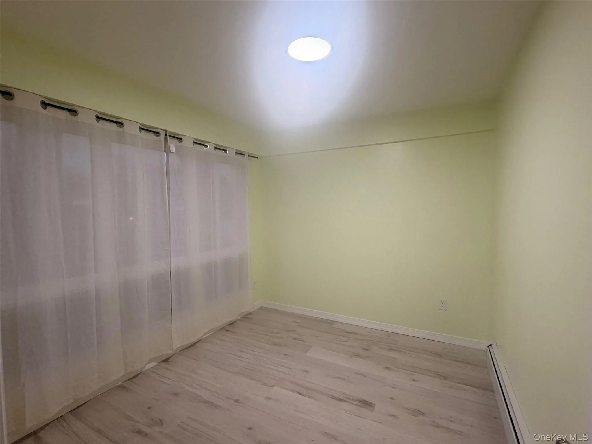 Downstairs spare room featuring a baseboard radiator and light wood-style floors Downstairs spare room featuring a baseboard radiator and light wood-style floors