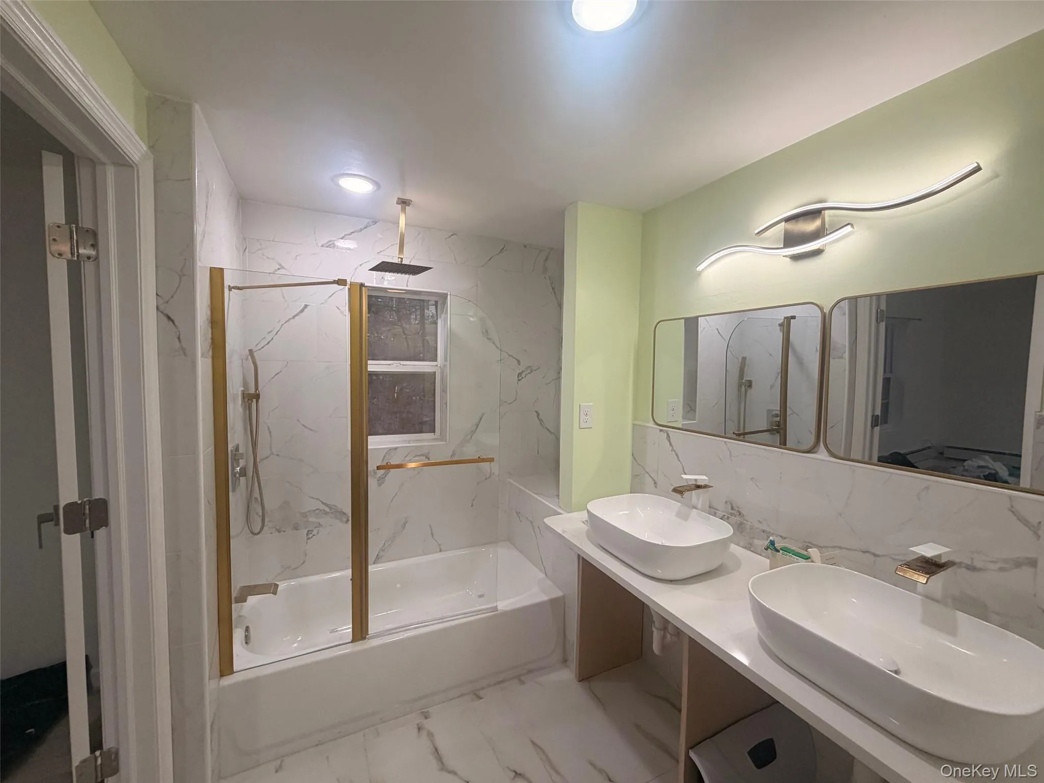 Primary Bathroom with light marble finish flooring, double vanity, and a combined bath / shower with rainfall shower Primary Bathroom with light marble finish flooring, double vanity, and a combined bath / shower with rainfall shower