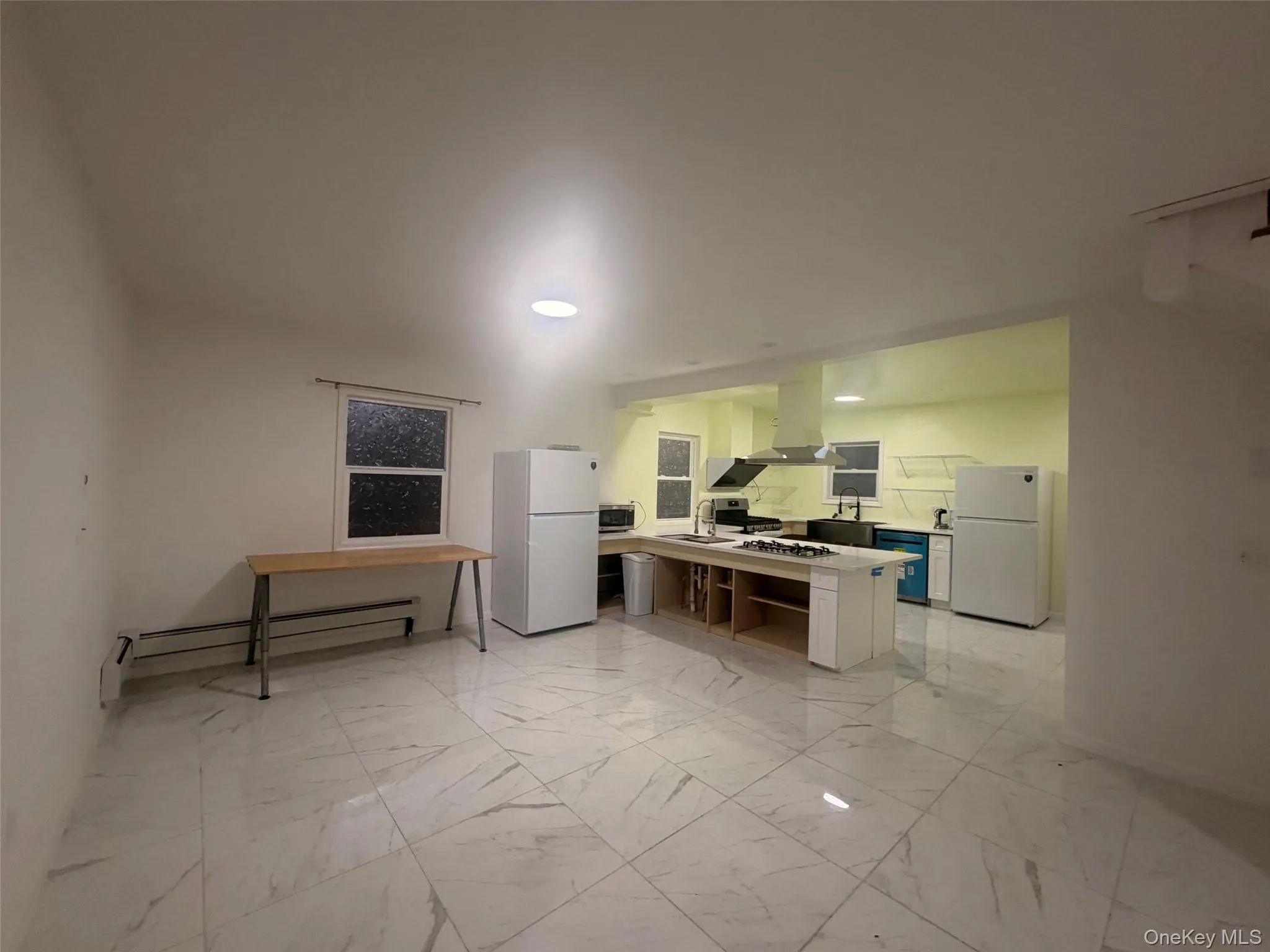 Kitchen with freestanding refrigerator, light countertops, baseboard heating, and light marble finish flooring Kitchen with freestanding refrigerator, light countertops, baseboard heating, and light marble finish flooring