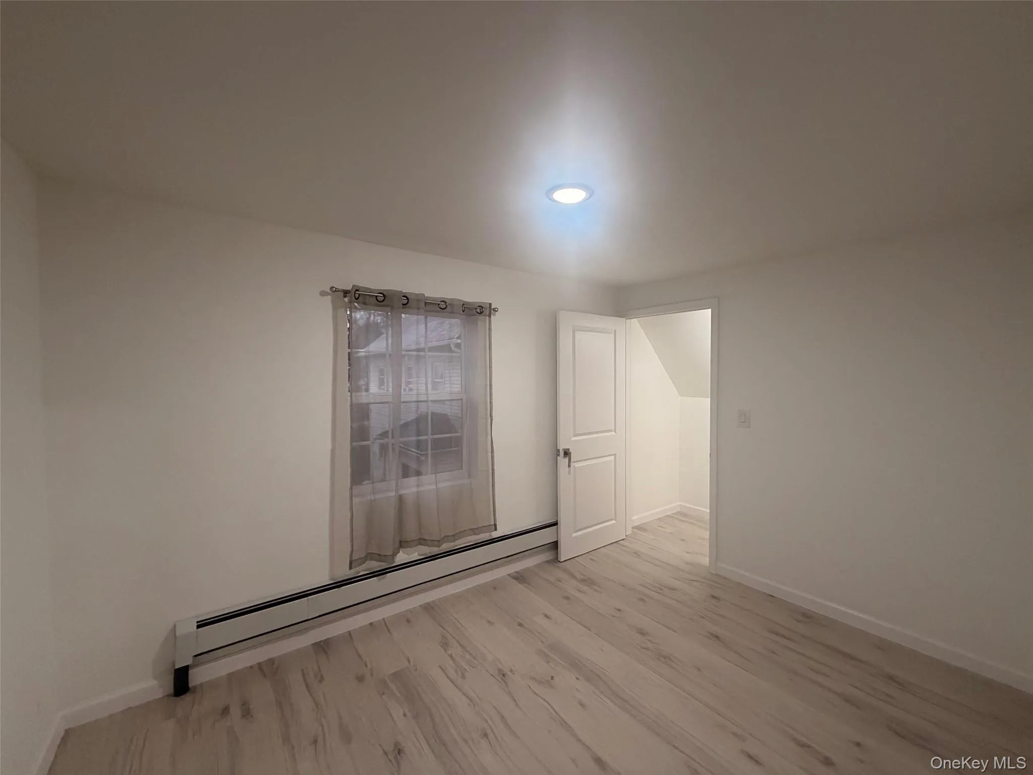 Bedroom featuring baseboard heating and light wood-style flooring Bedroom featuring baseboard heating and light wood-style flooring