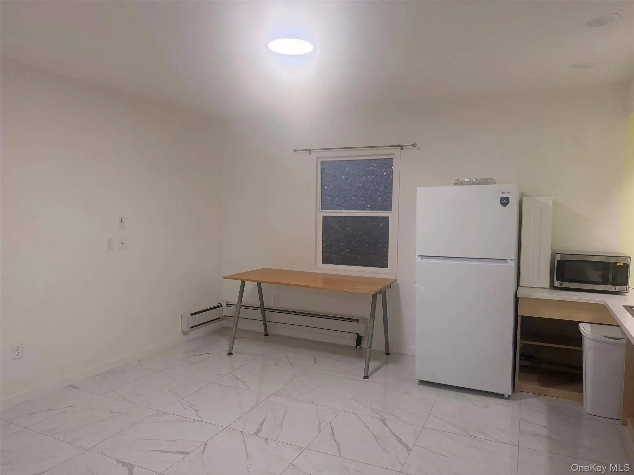 Dining area with light marble finish flooring and a baseboard radiator Dining area with light marble finish flooring and a baseboard radiator