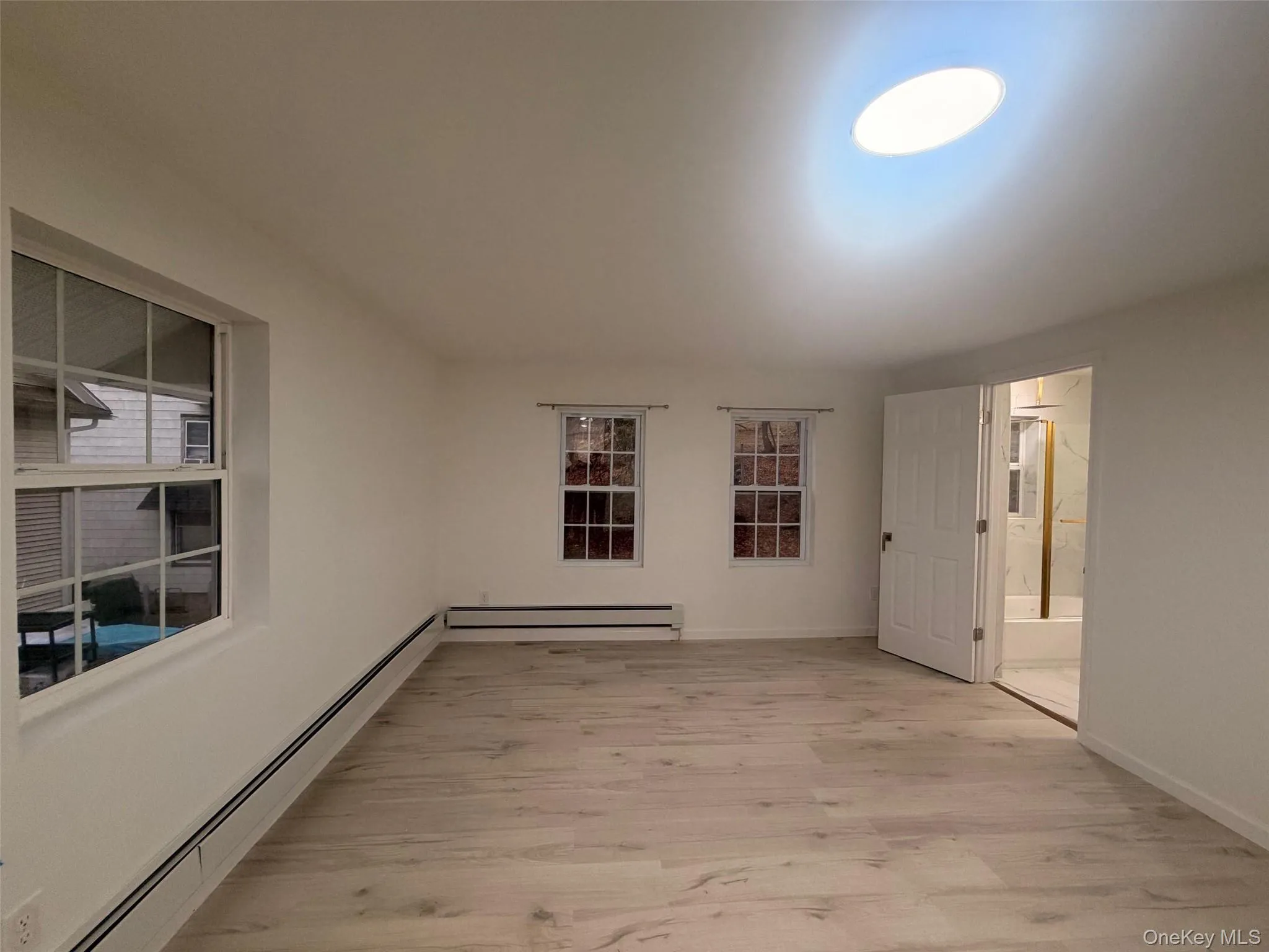 Upstairs Primary bedroom with a baseboard radiator and light wood finished floors Upstairs Primary bedroom with a baseboard radiator and light wood finished floors