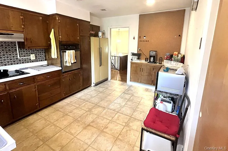 Kitchen featuring dark brown cabinetry, light countertops, oven, tasteful backsplash, and built in fridge Kitchen featuring dark brown cabinetry, light countertops, oven, tasteful backsplash, and built in fridge