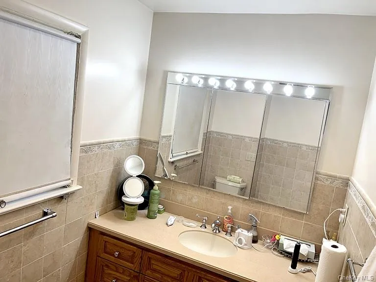 Bathroom with vanity, tile walls, and wainscoting Bathroom with vanity, tile walls, and wainscoting