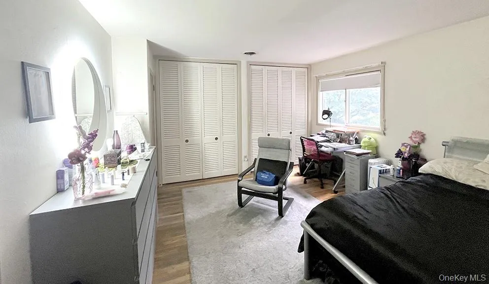 Bedroom with two closets, light wood-style floors, an office area, and a textured wall Bedroom with two closets, light wood-style floors, an office area, and a textured wall