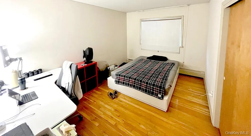 Bedroom with light wood-style flooring and an office area Bedroom with light wood-style flooring and an office area