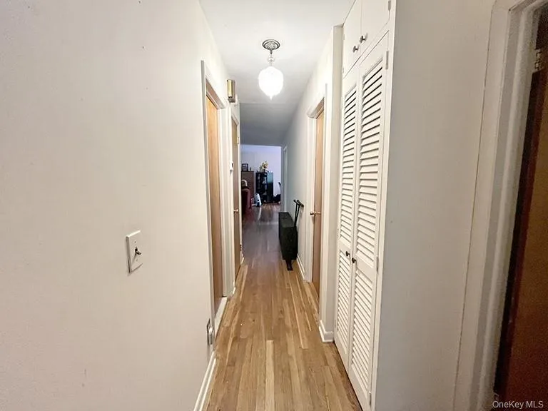 Hallway featuring baseboards and light wood-type flooring Hallway featuring baseboards and light wood-type flooring