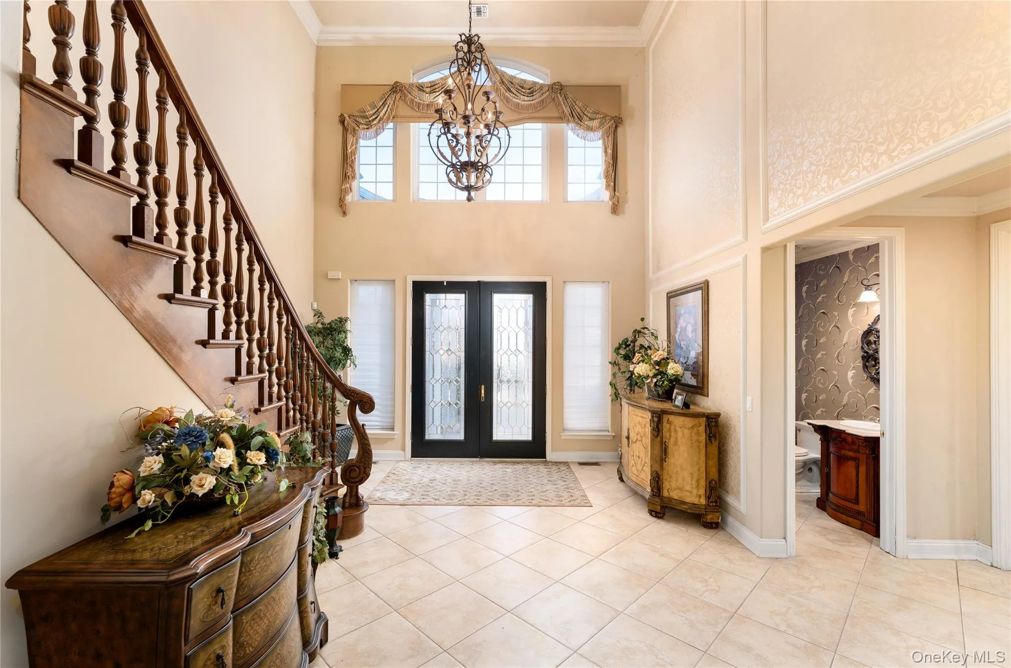 Foyer featuring ornamental molding, french doors, light tile patterned floors, a chandelier, and stairway Foyer featuring ornamental molding, french doors, light tile patterned floors, a chandelier, and stairway