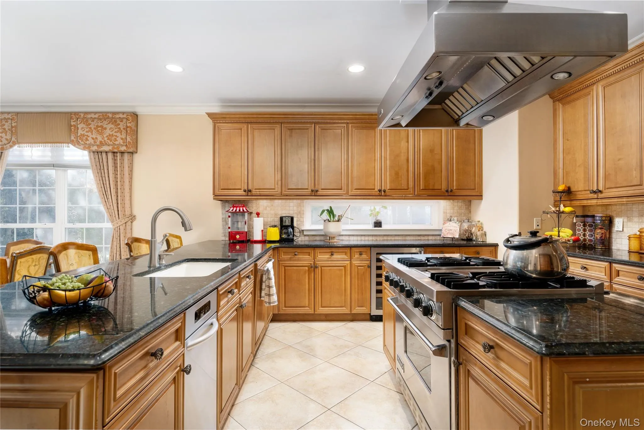 Kitchen with dark stone countertops, stainless steel gas stove, extractor fan, a peninsula, and recessed lighting Kitchen with dark stone countertops, stainless steel gas stove, extractor fan, a peninsula, and recessed lighting