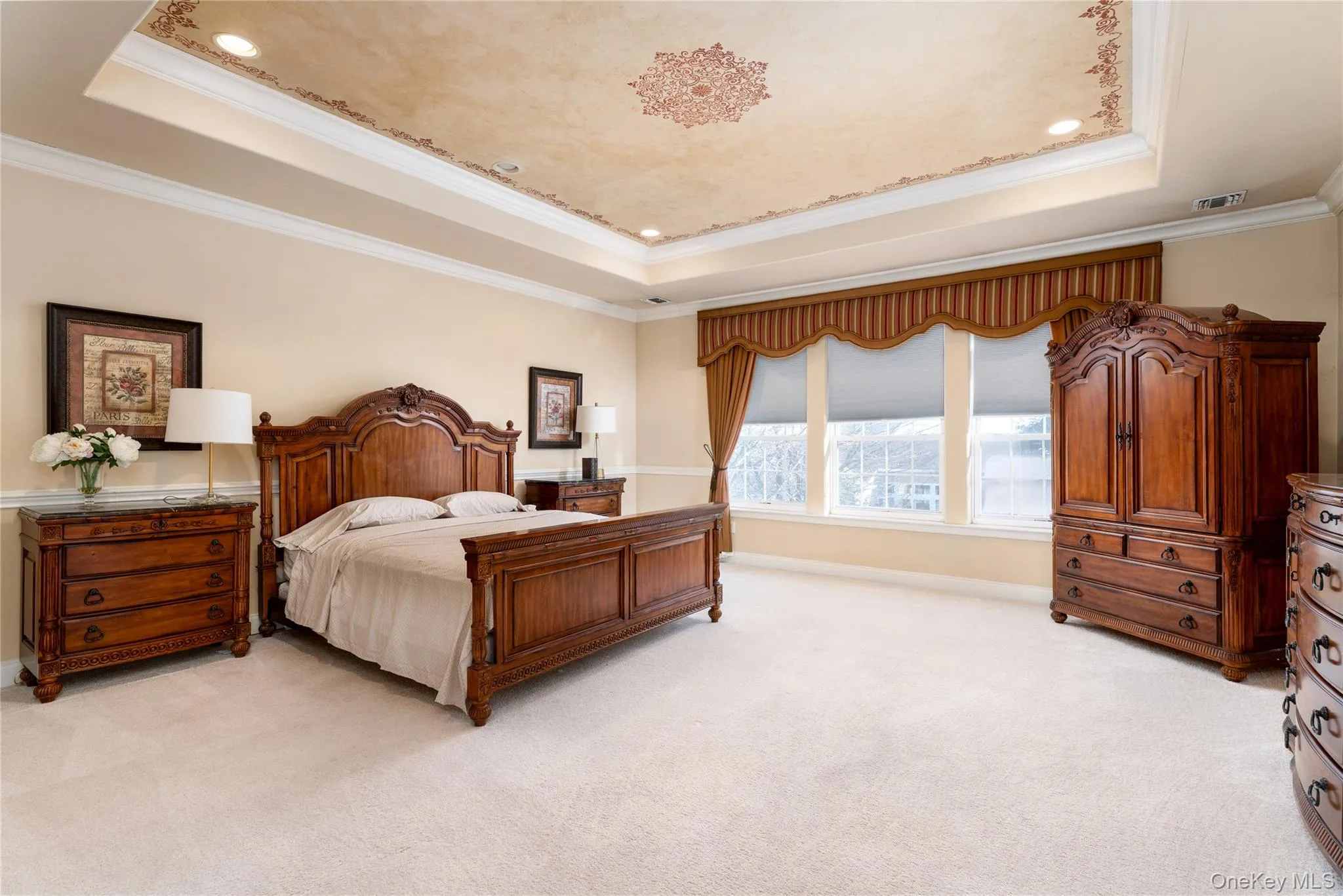 Bedroom featuring a raised ceiling, ornamental molding, and light colored carpet Bedroom featuring a raised ceiling, ornamental molding, and light colored carpet