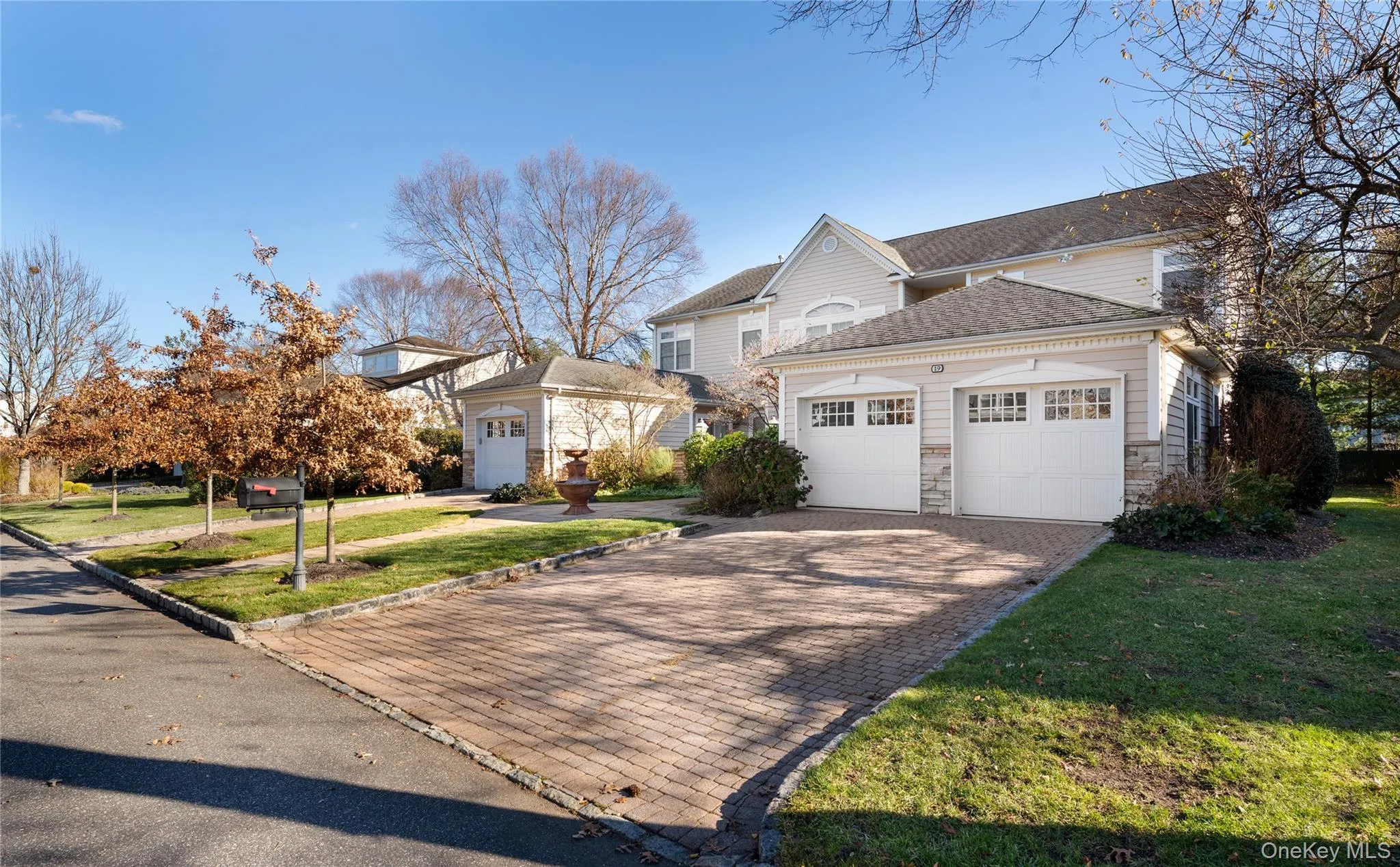 Traditional-style house featuring a shingled roof, stone siding, decorative driveway, a front yard, and a garage Traditional-style house featuring a shingled roof, stone siding, decorative driveway, a front yard, and a garage
