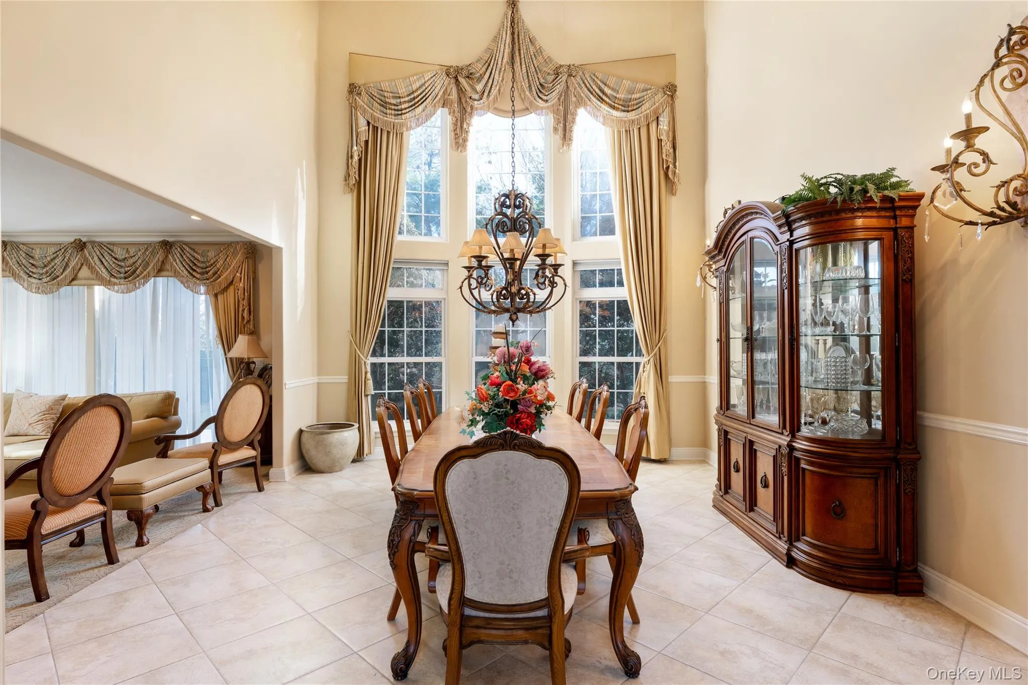 Dining room with a chandelier, tile patterned flooring, and a towering ceiling Dining room with a chandelier, tile patterned flooring, and a towering ceiling