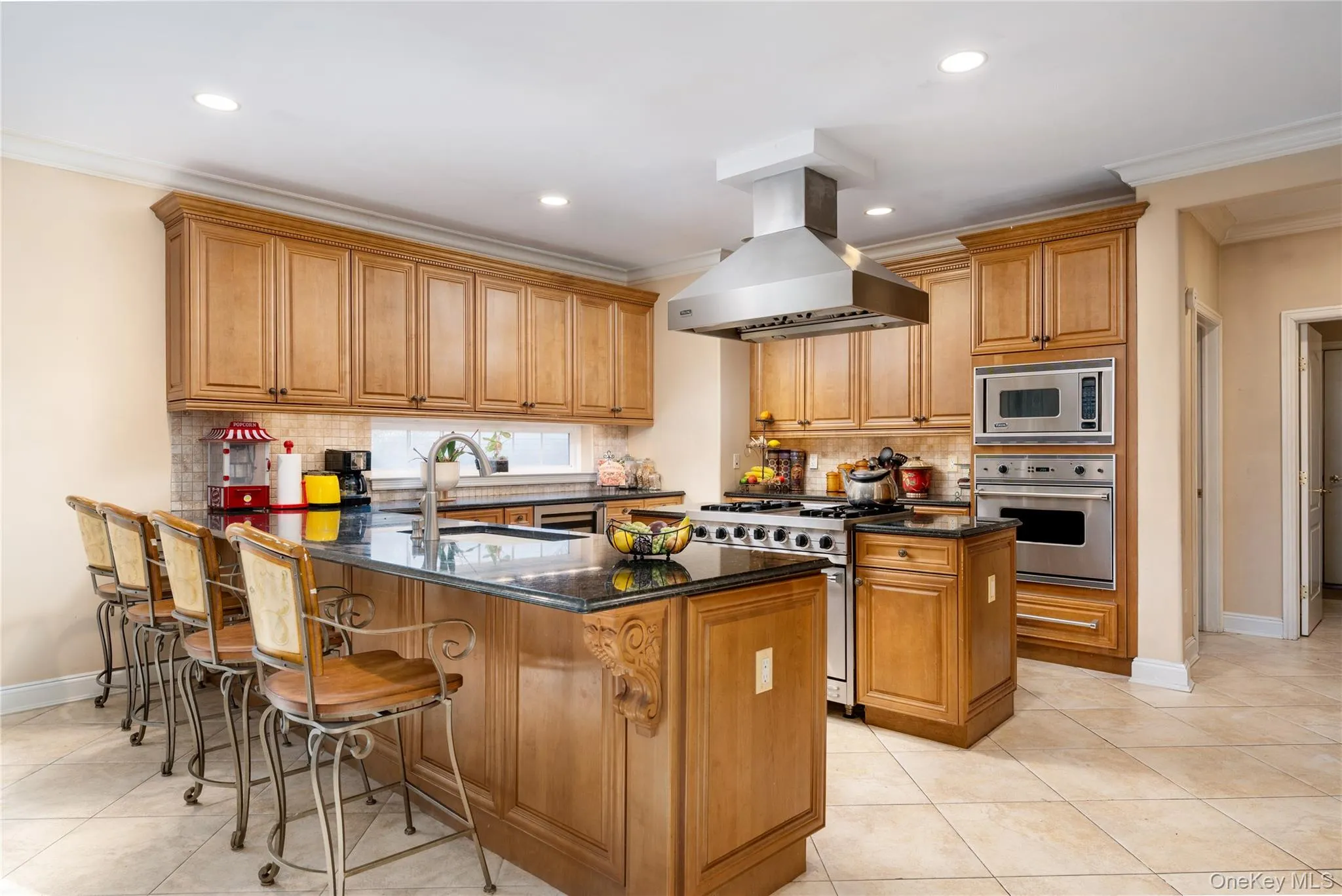 Kitchen featuring a peninsula, brown cabinetry, crown molding, appliances with stainless steel finishes, and decorative backsplash Kitchen featuring a peninsula, brown cabinetry, crown molding, appliances with stainless steel finishes, and decorative backsplash