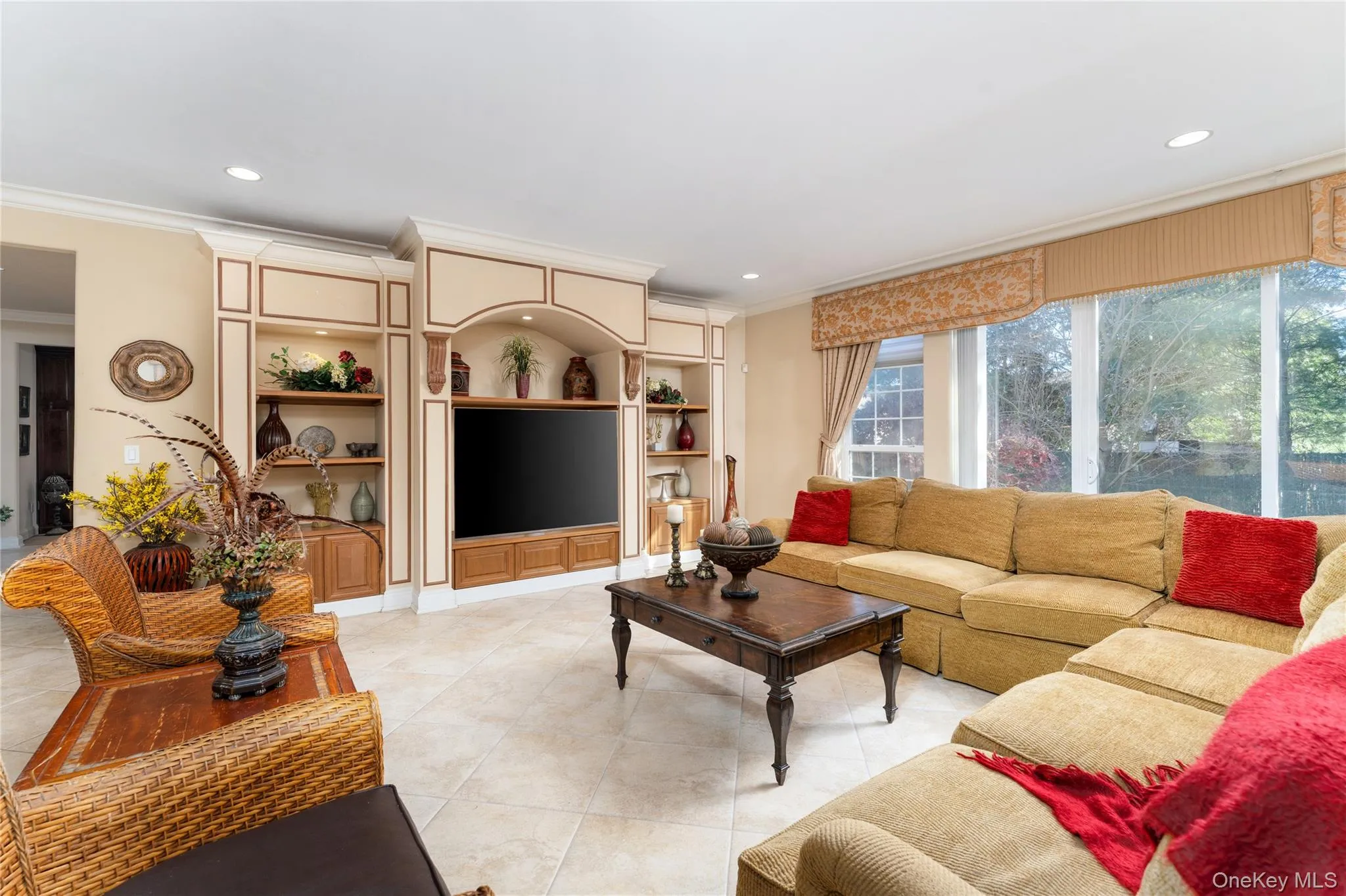 Living room featuring crown molding, recessed lighting, light tile patterned floors, and built in features Living room featuring crown molding, recessed lighting, light tile patterned floors, and built in features