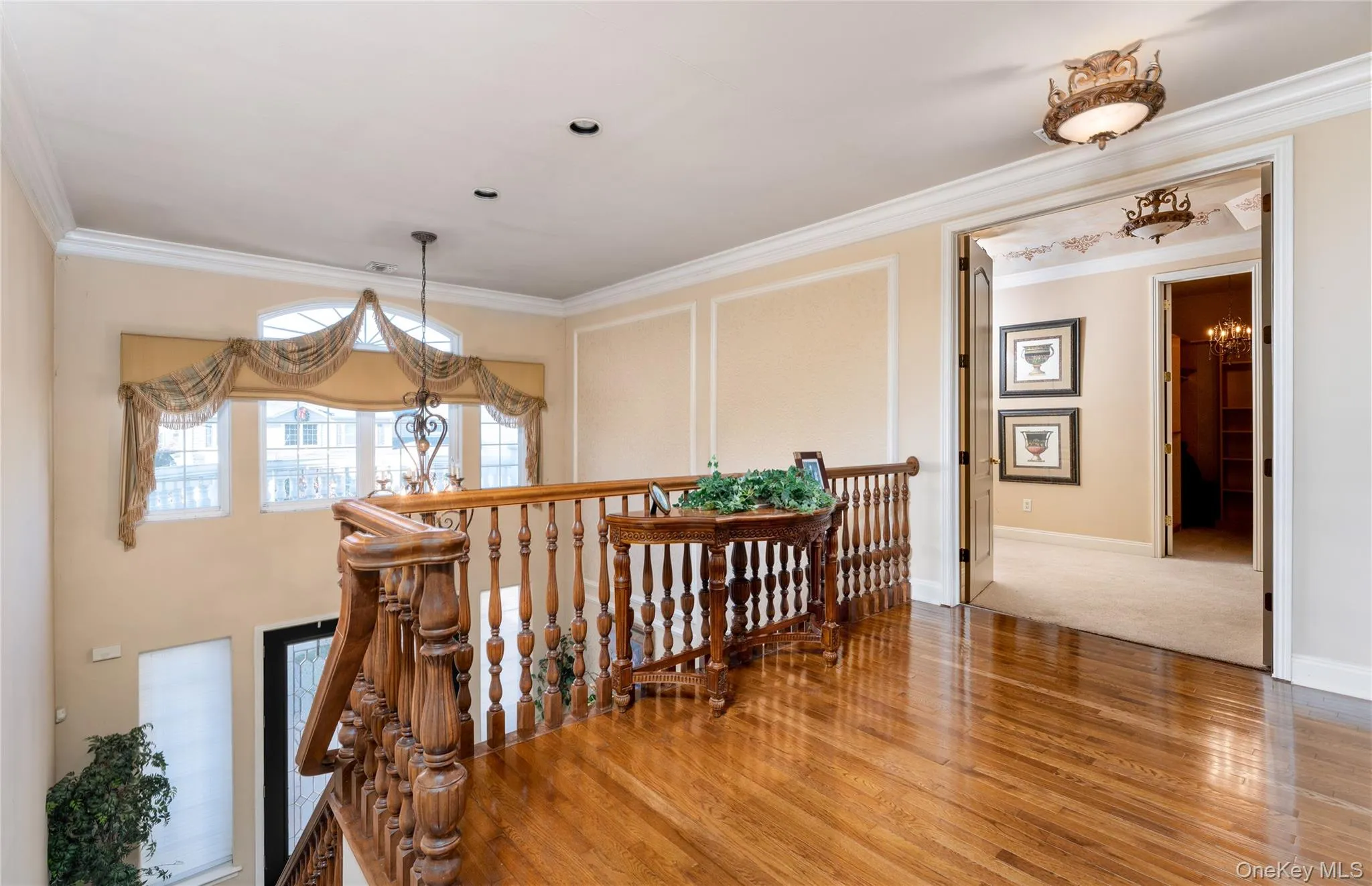 Corridor with an upstairs landing, a chandelier, crown molding, and wood finished floors Corridor with an upstairs landing, a chandelier, crown molding, and wood finished floors