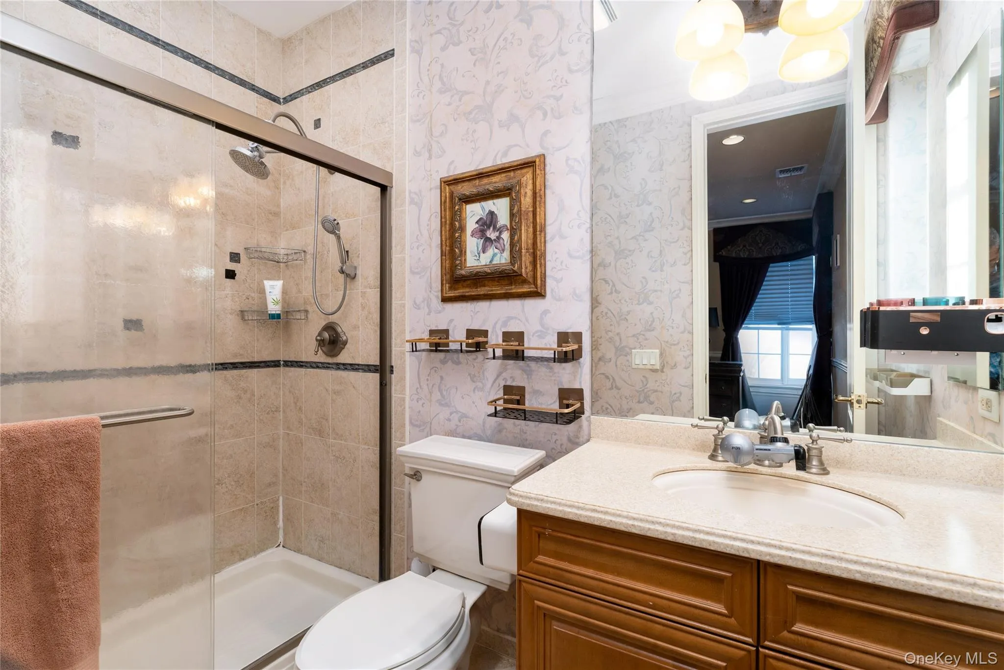 Full bath with wallpapered walls, vanity, a shower stall, a chandelier, and crown molding Full bath with wallpapered walls, vanity, a shower stall, a chandelier, and crown molding