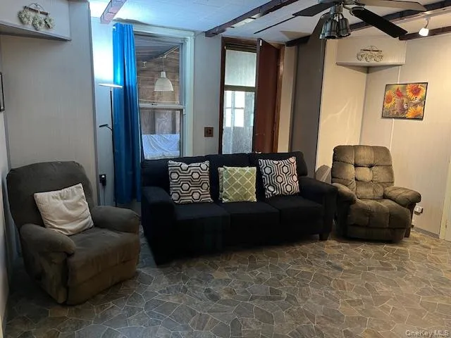 Living room featuring stone flooring and a ceiling fan Living room featuring stone flooring and a ceiling fan
