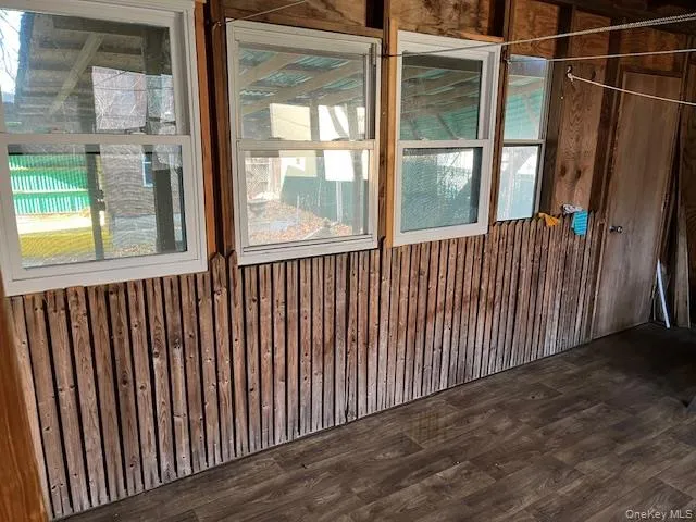 Spare room featuring wood walls and dark wood-style flooring Spare room featuring wood walls and dark wood-style flooring