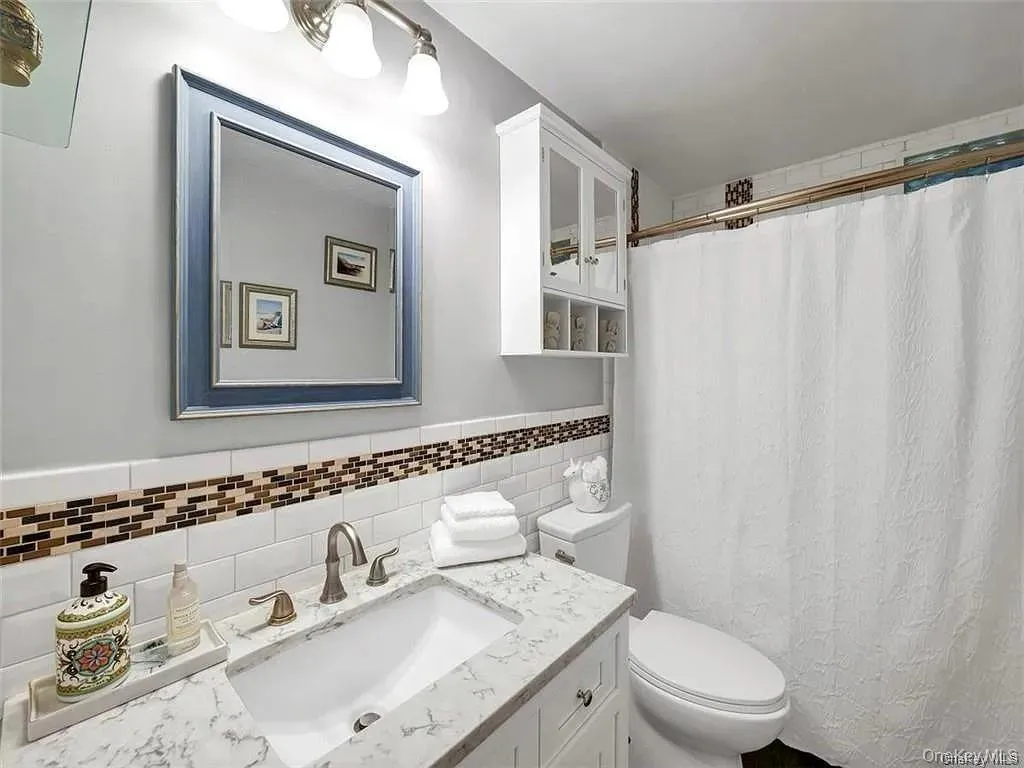 Bathroom with vanity, toilet, a shower with curtain, and backsplash Bathroom with vanity, toilet, a shower with curtain, and backsplash