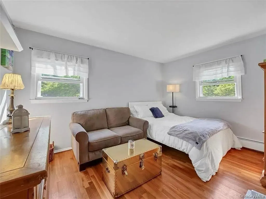 Bedroom with a baseboard heating unit, multiple windows, and light hardwood / wood-style floors Bedroom with a baseboard heating unit, multiple windows, and light hardwood / wood-style floors