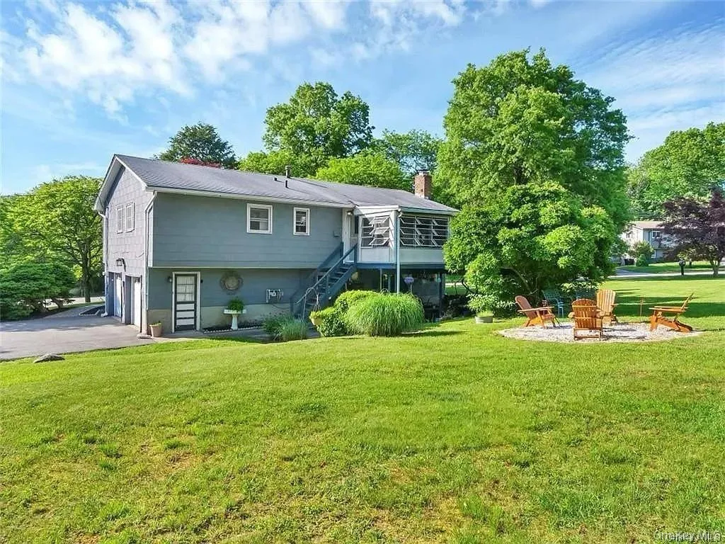 Rear view of house featuring an outdoor fire pit, a garage, and a yard Rear view of house featuring an outdoor fire pit, a garage, and a yard