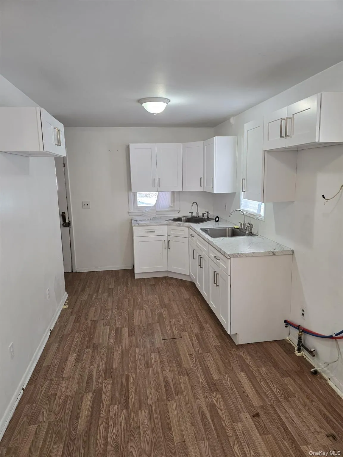 Kitchen featuring white cabinets, dark wood-type flooring, and light countertops Kitchen featuring white cabinets, dark wood-type flooring, and light countertops