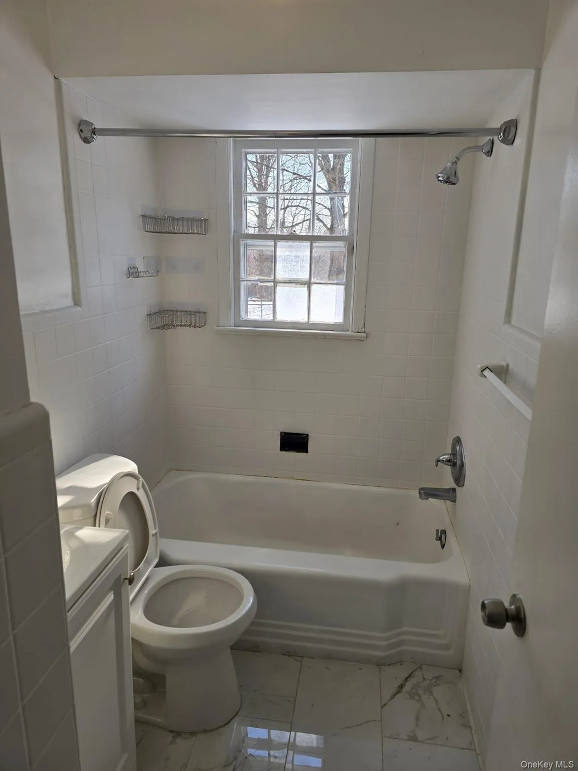 Bathroom with washtub / shower combination, vanity, and light marble finish flooring Bathroom with washtub / shower combination, vanity, and light marble finish flooring