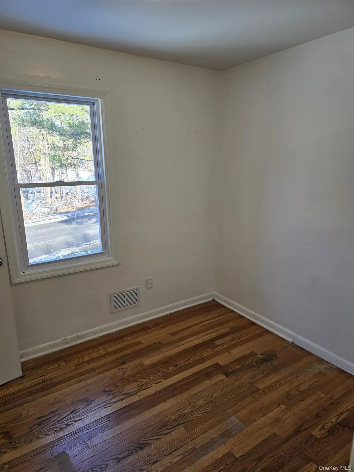 Spare room with dark wood-type flooring and baseboards Spare room with dark wood-type flooring and baseboards