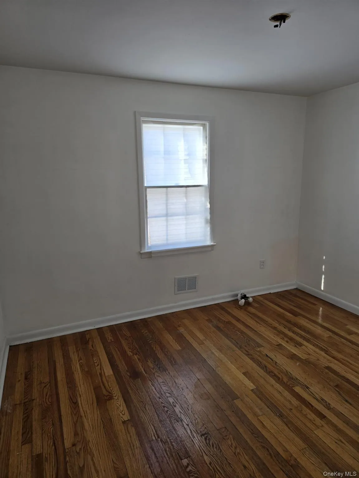 Unfurnished room with dark wood-style flooring and baseboards Unfurnished room with dark wood-style flooring and baseboards