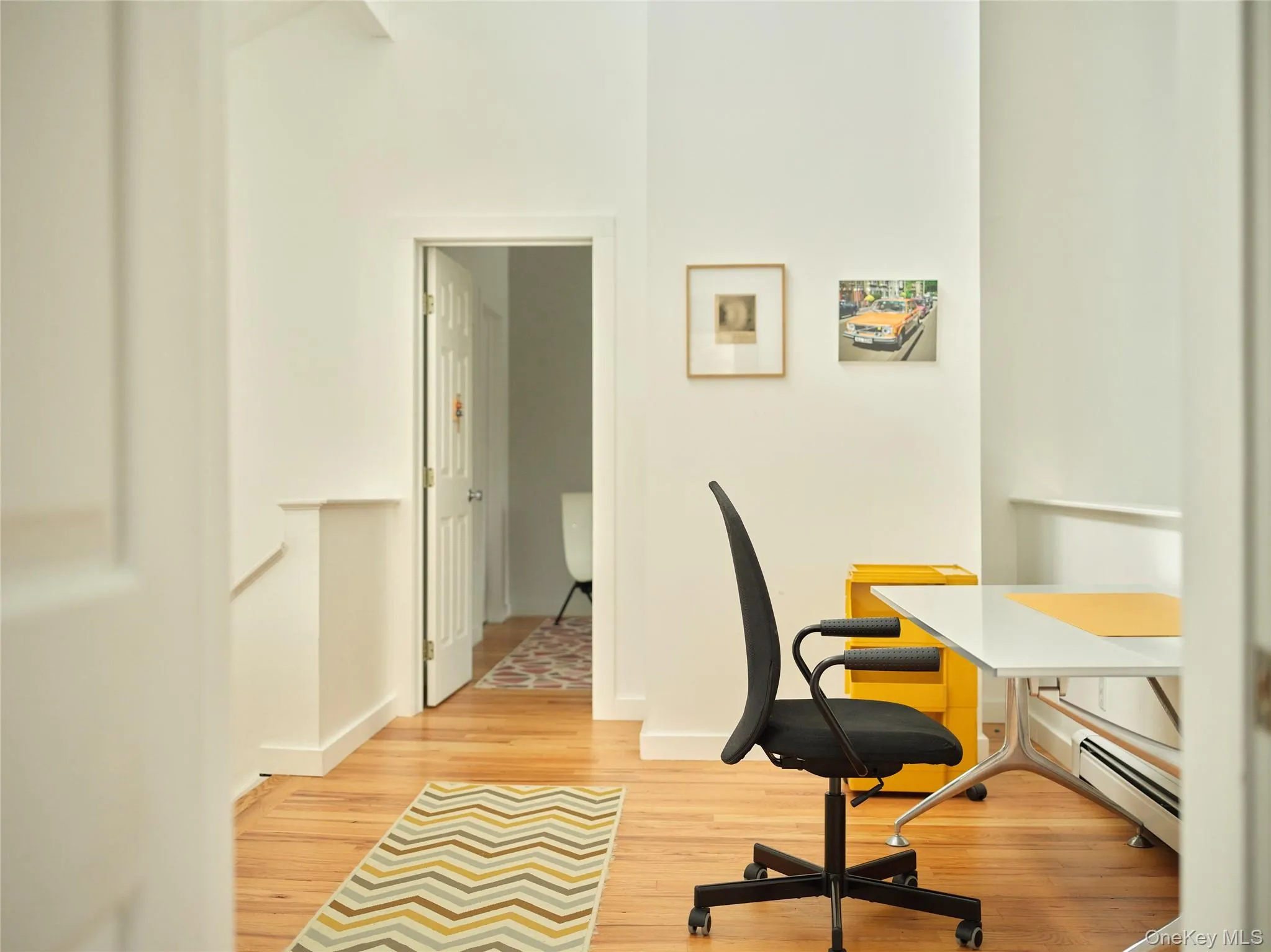 Home office with baseboard heating and light wood-type flooring Home office with baseboard heating and light wood-type flooring