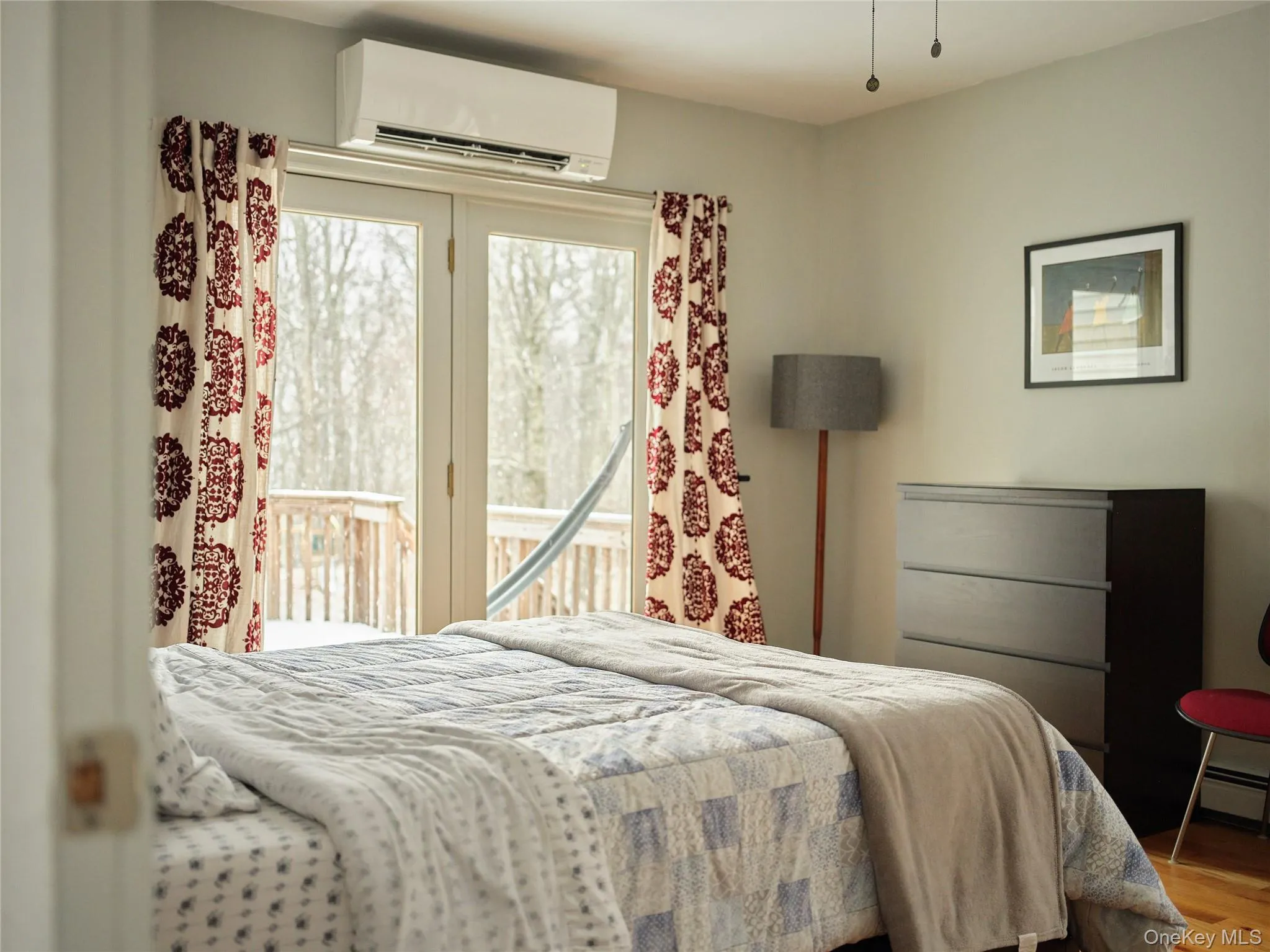 Bedroom featuring a wall unit AC, access to exterior, and wood finished floors Bedroom featuring a wall unit AC, access to exterior, and wood finished floors