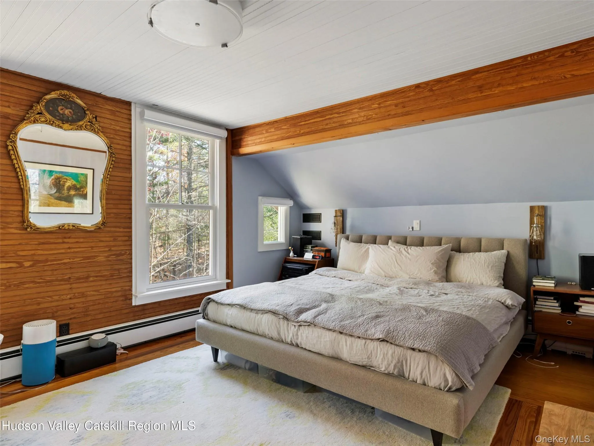 Bedroom with wood finished floors, an office area, and baseboard heating Bedroom with wood finished floors, an office area, and baseboard heating