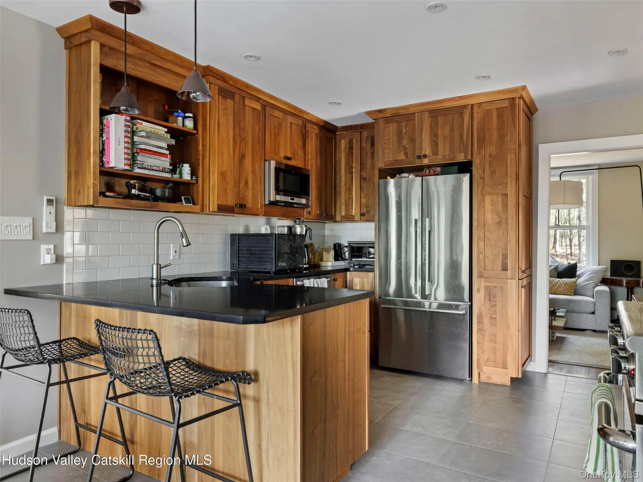 Kitchen featuring stainless steel appliances, a peninsula, decorative light fixtures, brown cabinetry, and a breakfast bar area Kitchen featuring stainless steel appliances, a peninsula, decorative light fixtures, brown cabinetry, and a breakfast bar area