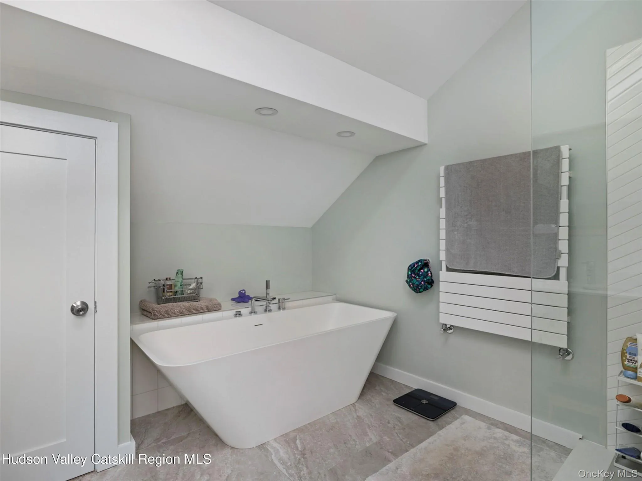 Full bath with lofted ceiling, a freestanding bath, radiator heating unit, and a towel warming rack Full bath with lofted ceiling, a freestanding bath, radiator heating unit, and a towel warming rack