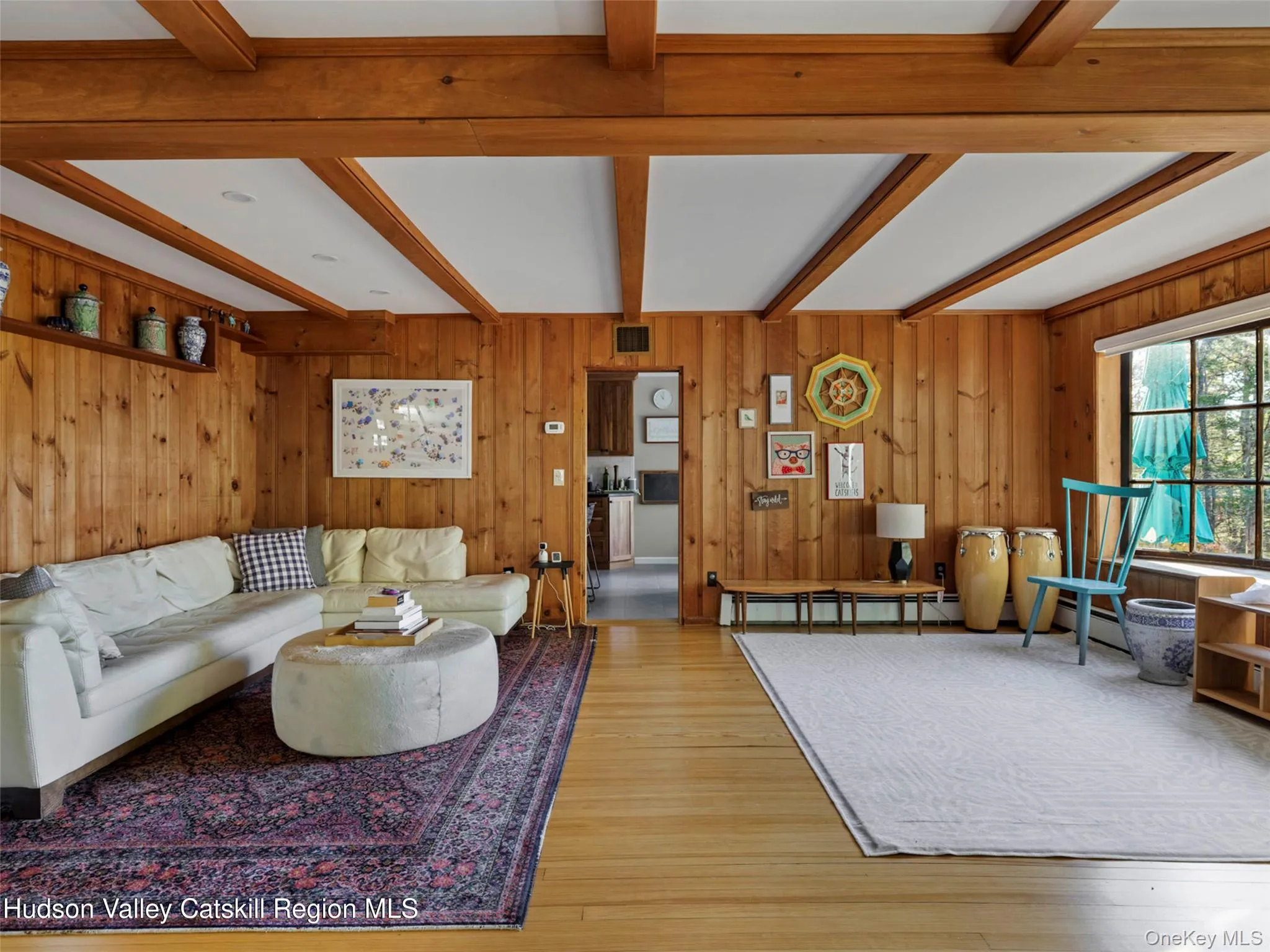 Living area with wooden walls, beam ceiling, and hardwood / wood-style flooring Living area with wooden walls, beam ceiling, and hardwood / wood-style flooring