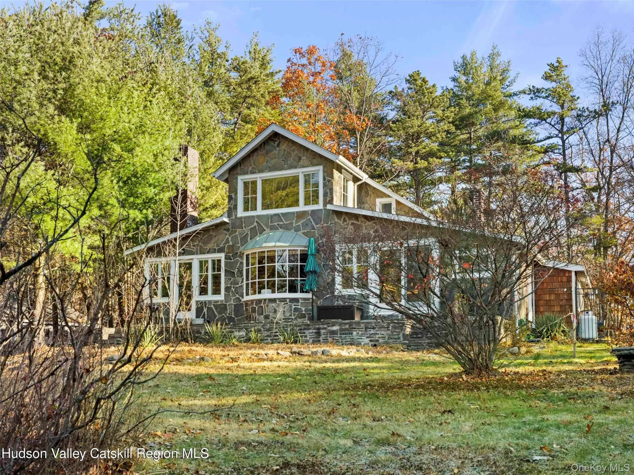 Back of property featuring stone siding and a lawn Back of property featuring stone siding and a lawn