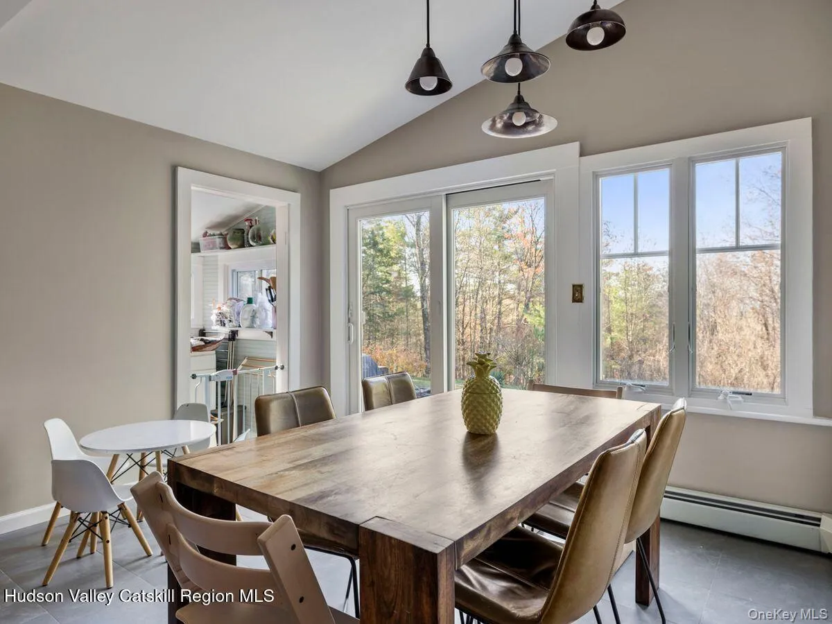Dining room featuring lofted ceiling, healthy amount of natural light, a baseboard heating unit, and tile patterned flooring Dining room featuring lofted ceiling, healthy amount of natural light, a baseboard heating unit, and tile patterned flooring