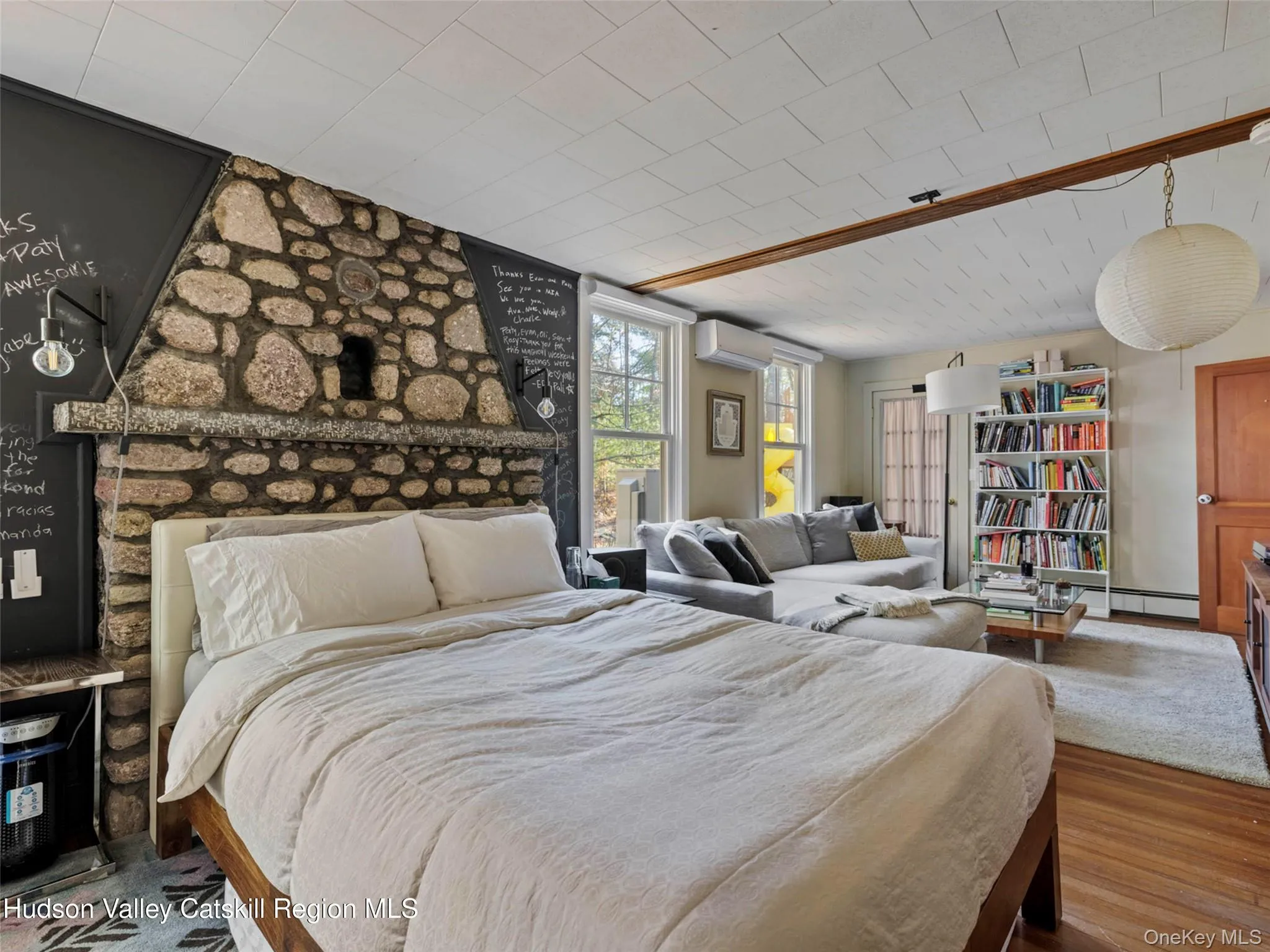 Bedroom featuring a wall mounted air conditioner, wood finished floors, and a baseboard heating unit Bedroom featuring a wall mounted air conditioner, wood finished floors, and a baseboard heating unit