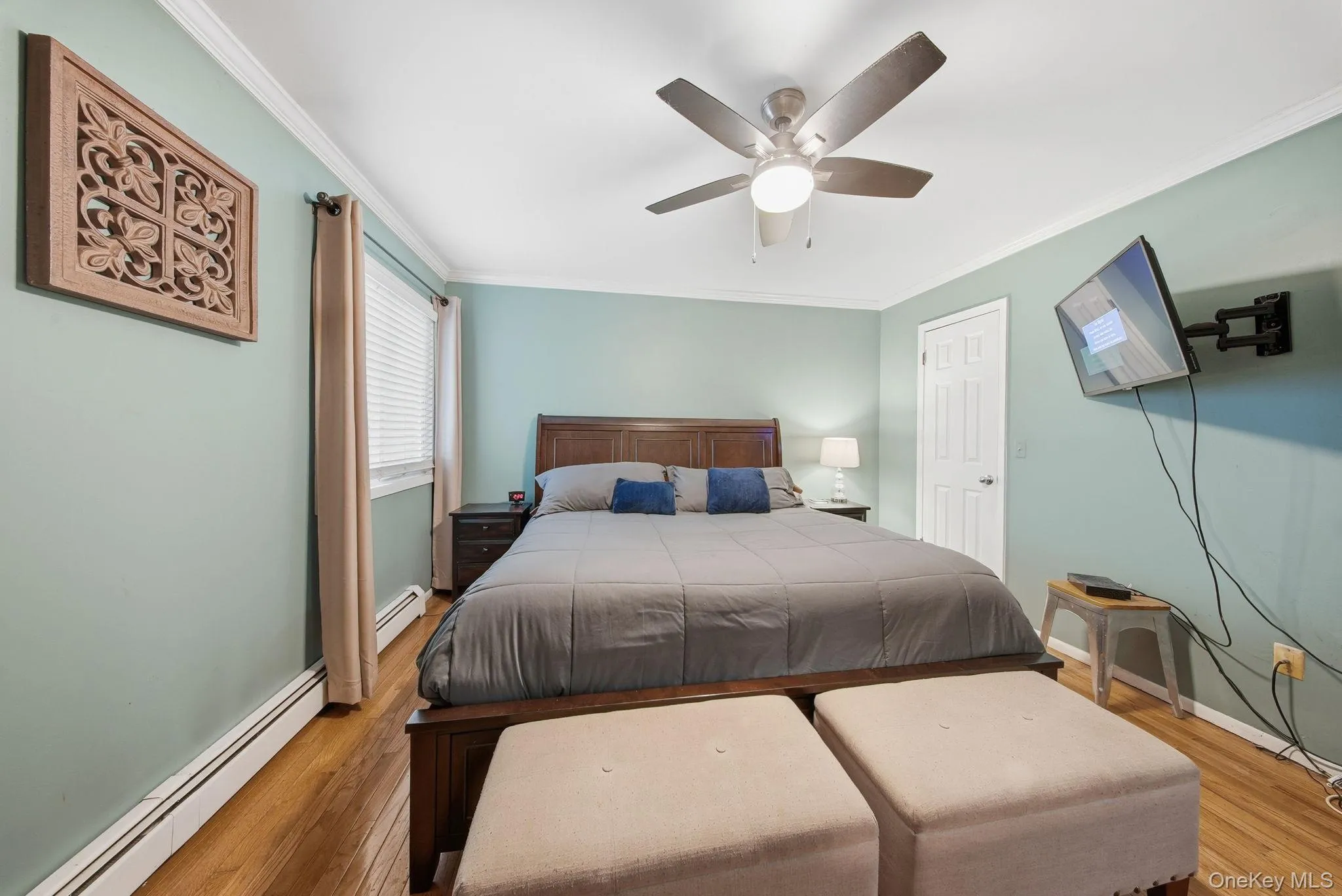Bedroom with a baseboard heating unit, crown molding, ceiling fan, and light wood-style floors Bedroom with a baseboard heating unit, crown molding, ceiling fan, and light wood-style floors